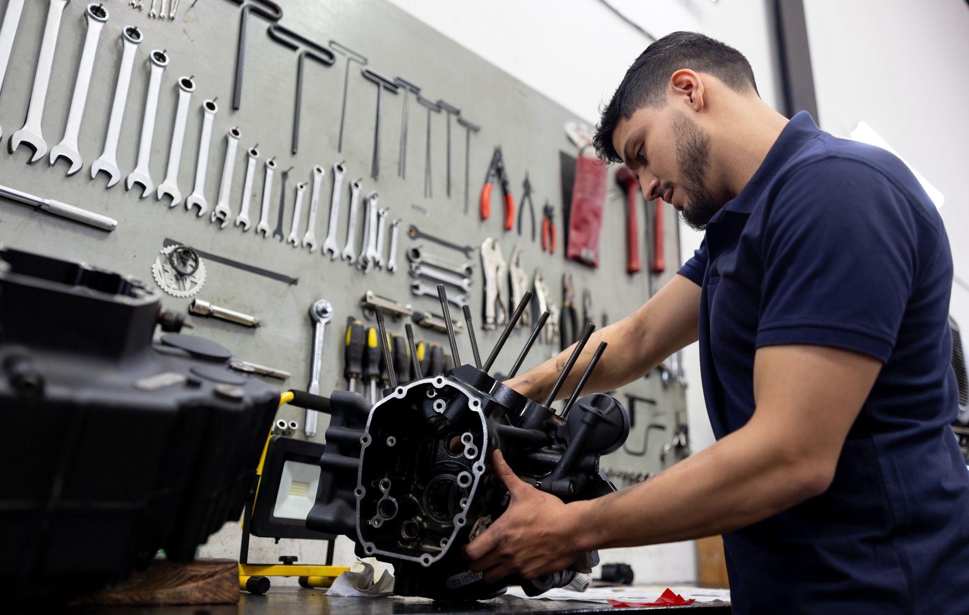 Un uomo sta lavorando sul motore di una motocicletta in un garage.