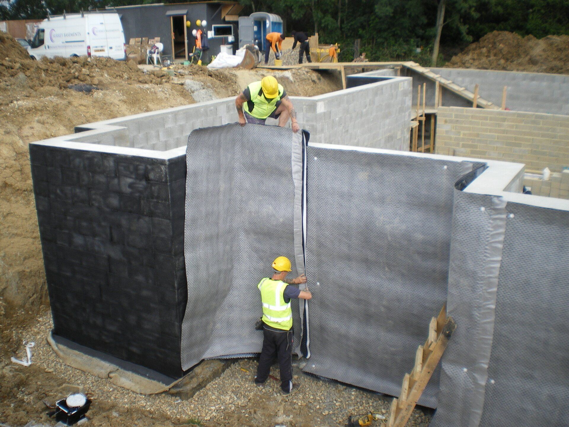 Two construction workers are measuring a wall with a tape measure