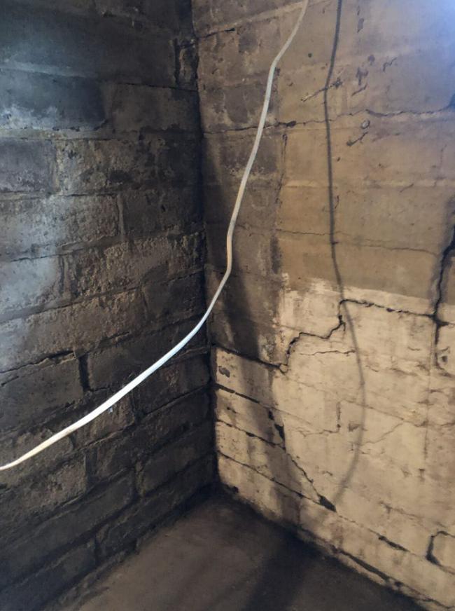 A brick wall with a white wire hanging from it