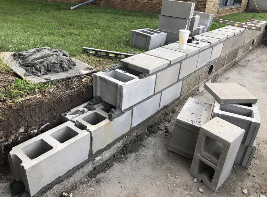 A brick wall is being built on the side of a road.