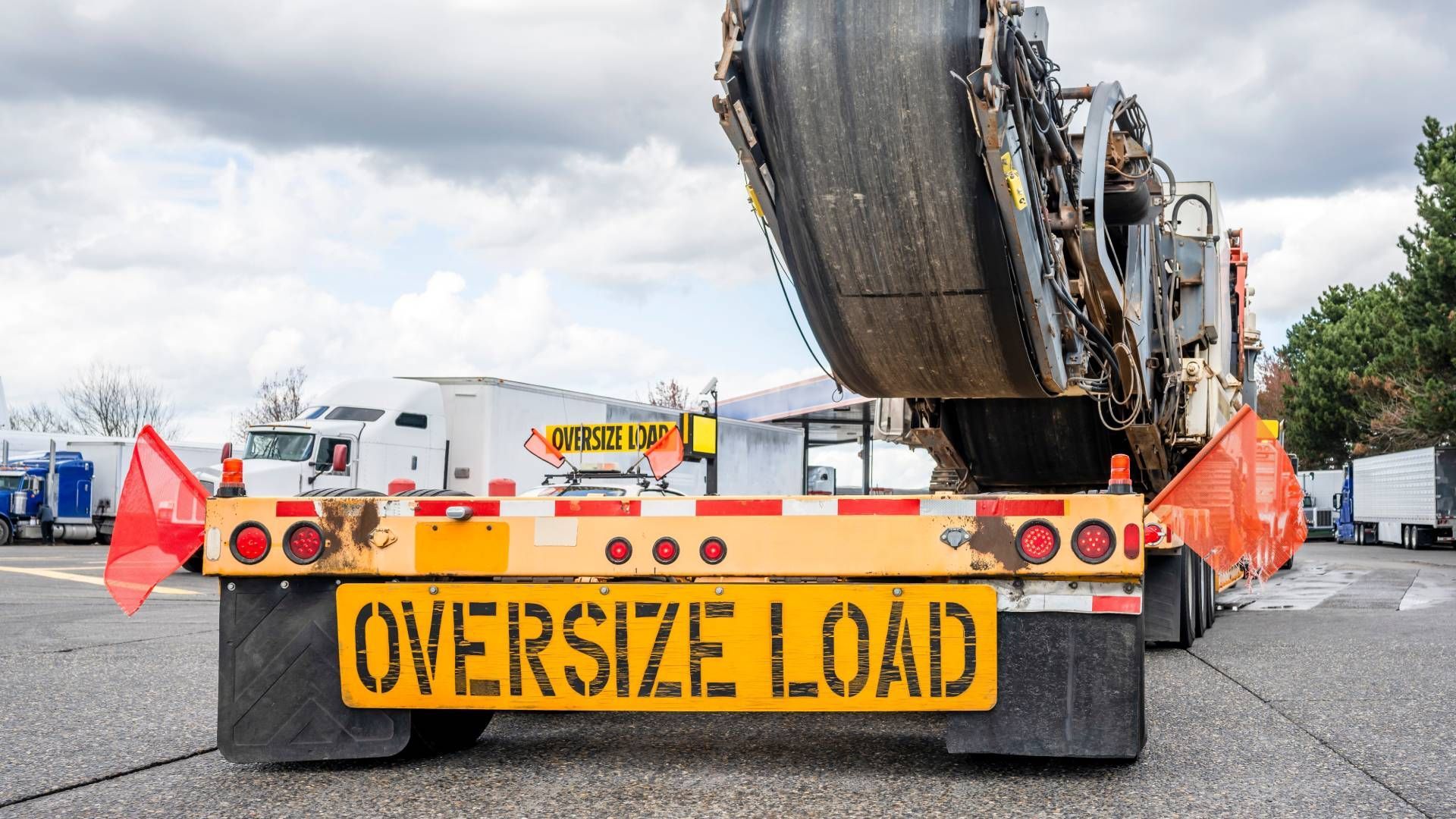 Rear view of oversized load trailer, yellow and orange, transporting large machine.