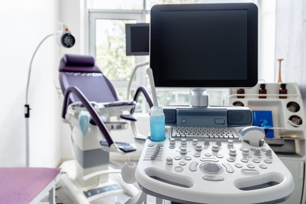 Ultrasound machine in a medical exam room with a purple examination chair.