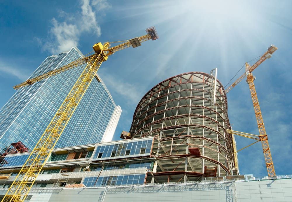 Construction site with cranes and buildings under a bright blue sky.