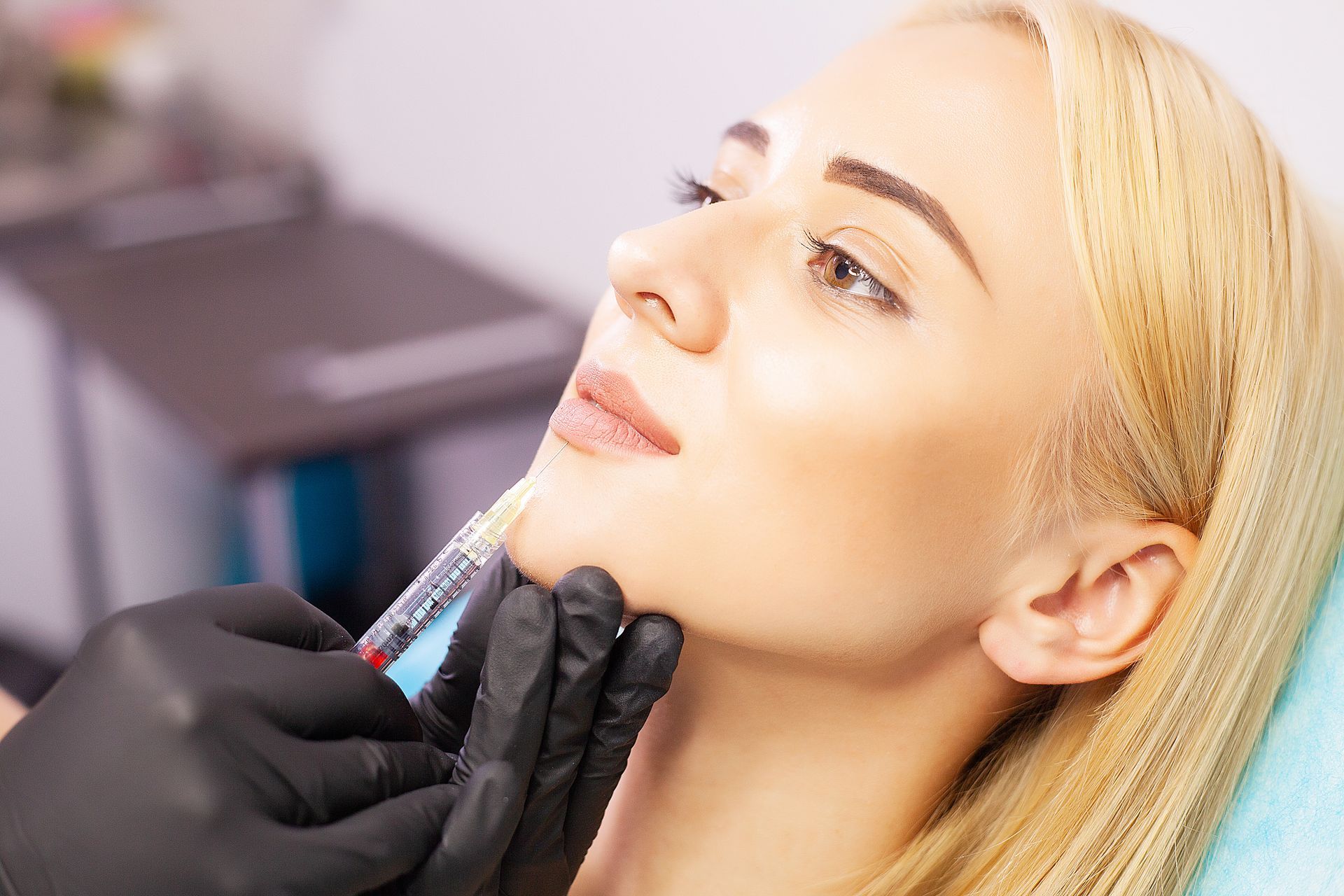 A woman is getting a botox injection in her face.