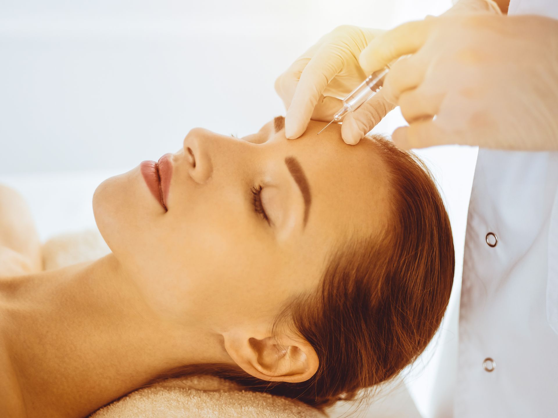 A woman is getting a botox injection in her forehead.