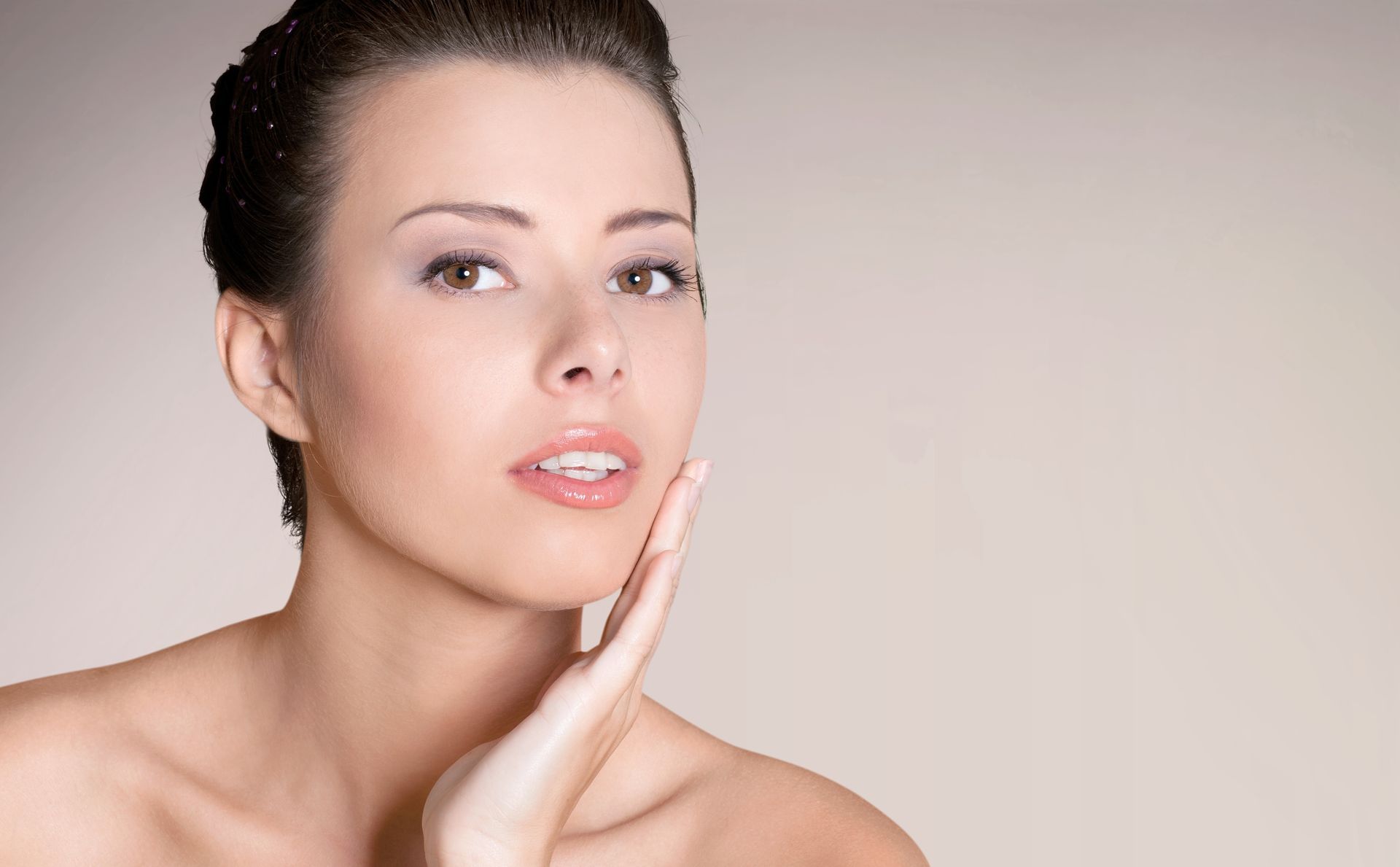 A woman is touching her face with her hand and looking at the camera.