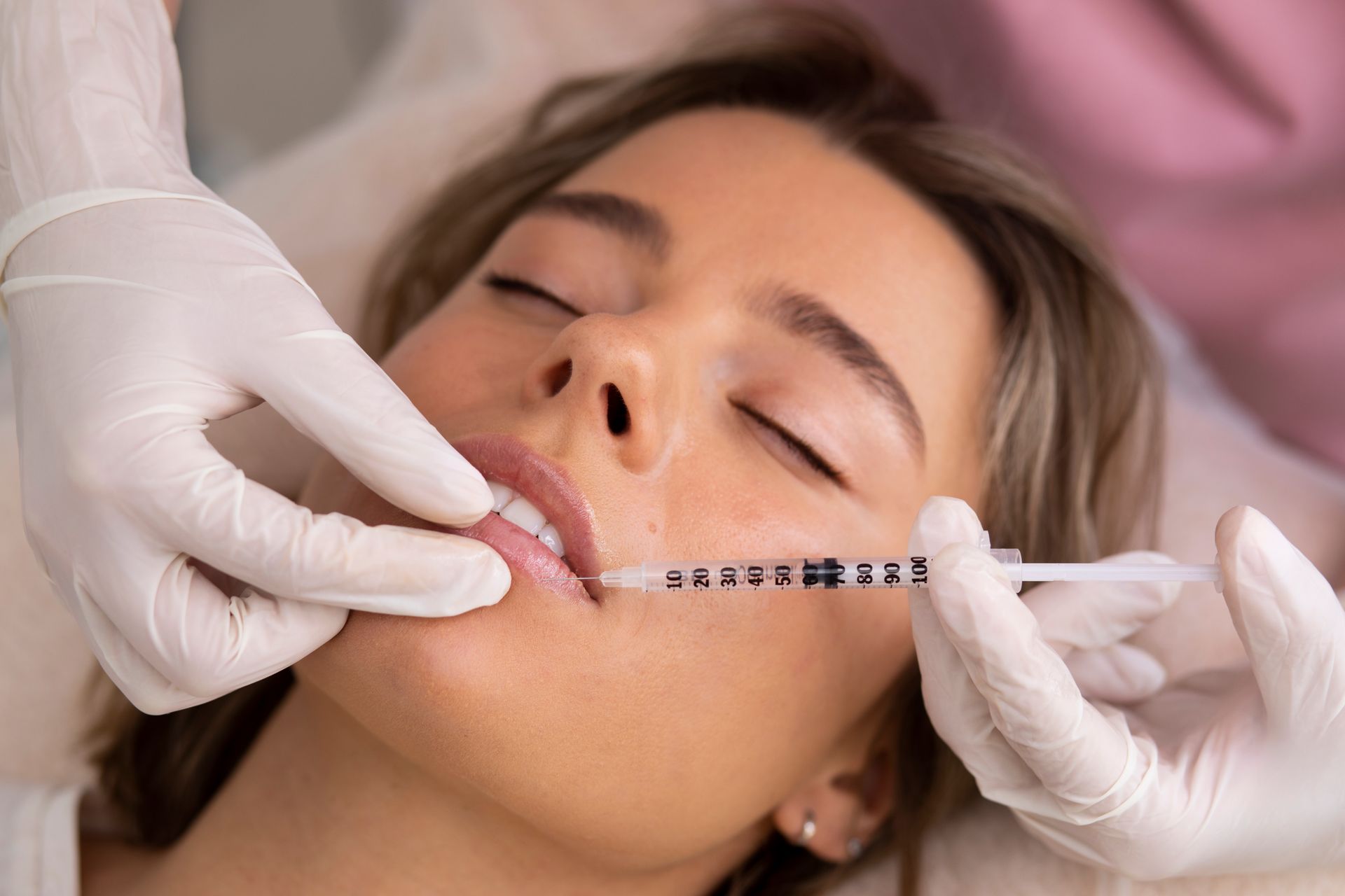 A woman is getting a botox injection in her lips.