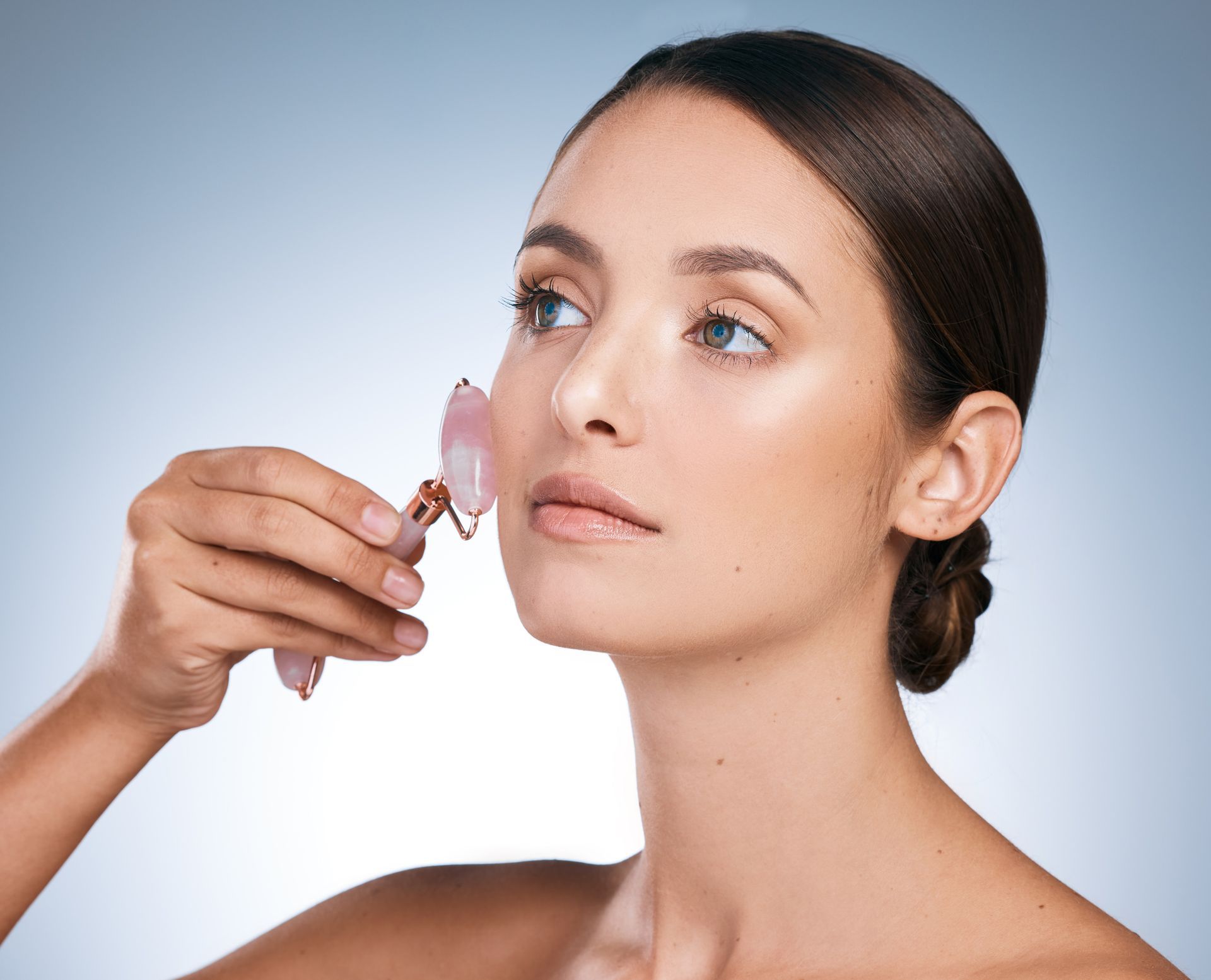 A woman is using a facial roller on her face.