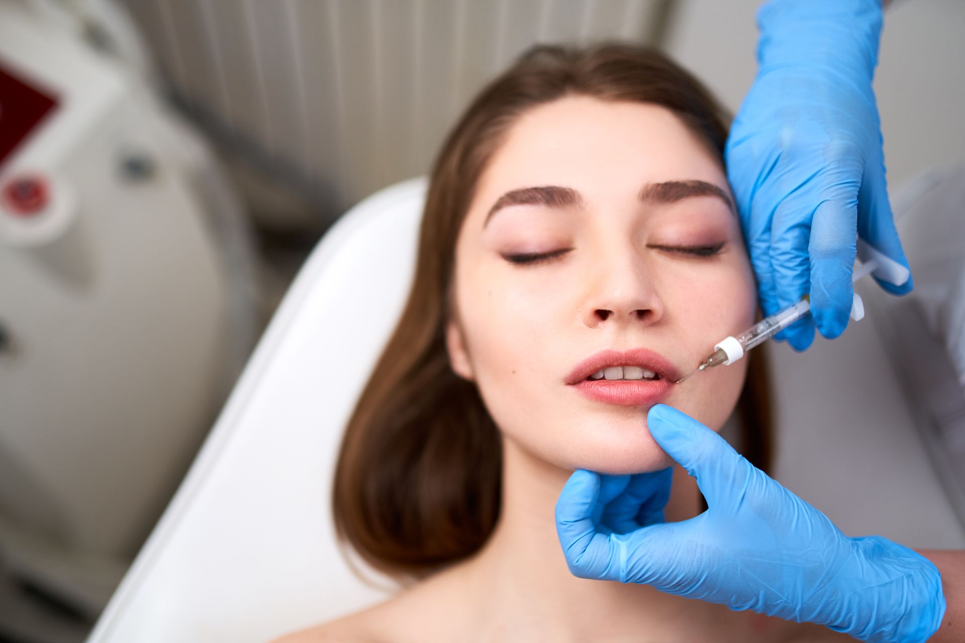 A woman is getting a botox injection in her lips.