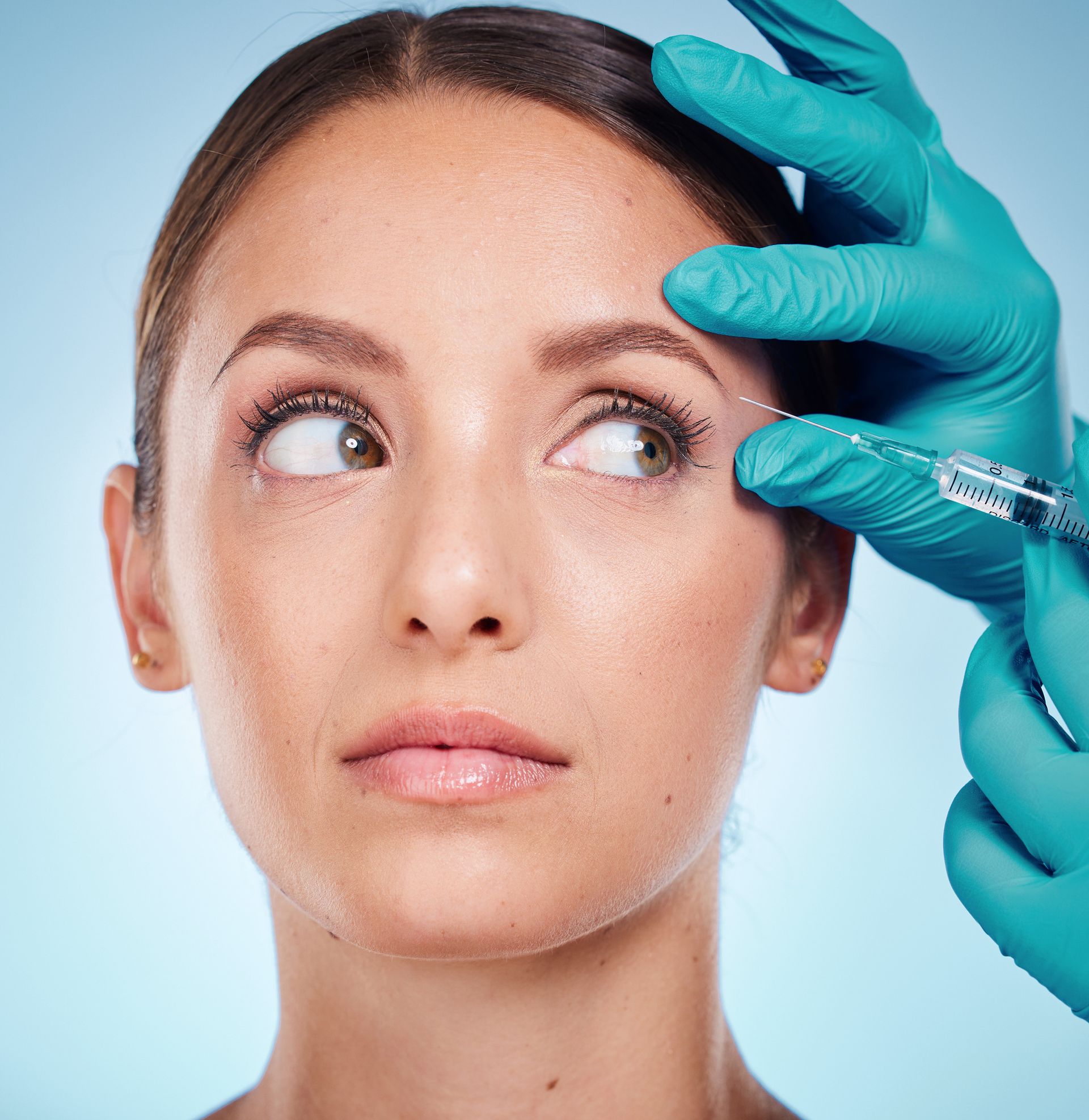 A woman is getting a botox injection in her forehead