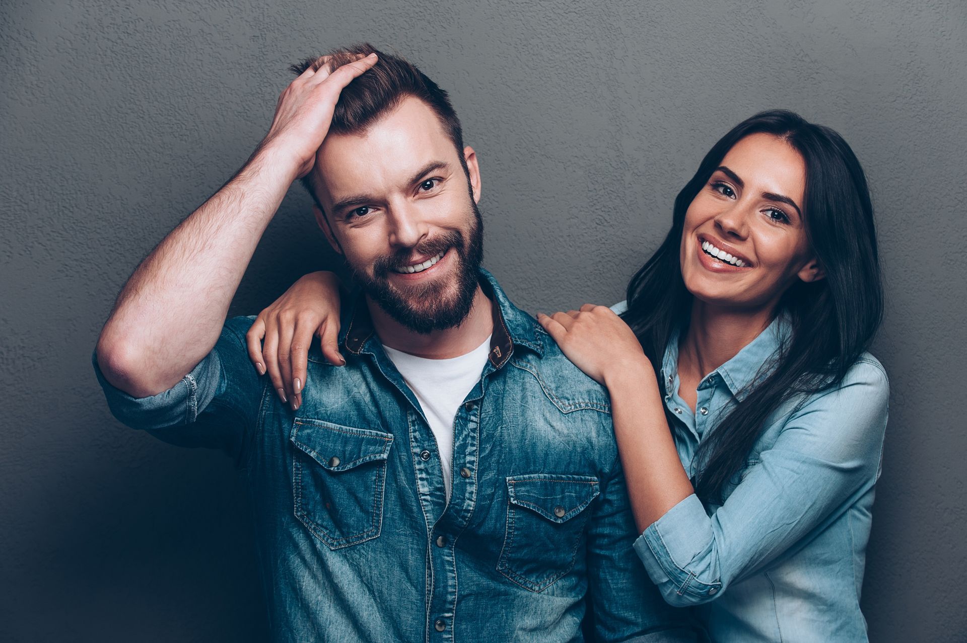 A man and a woman are posing for a picture and the woman is hugging the man.