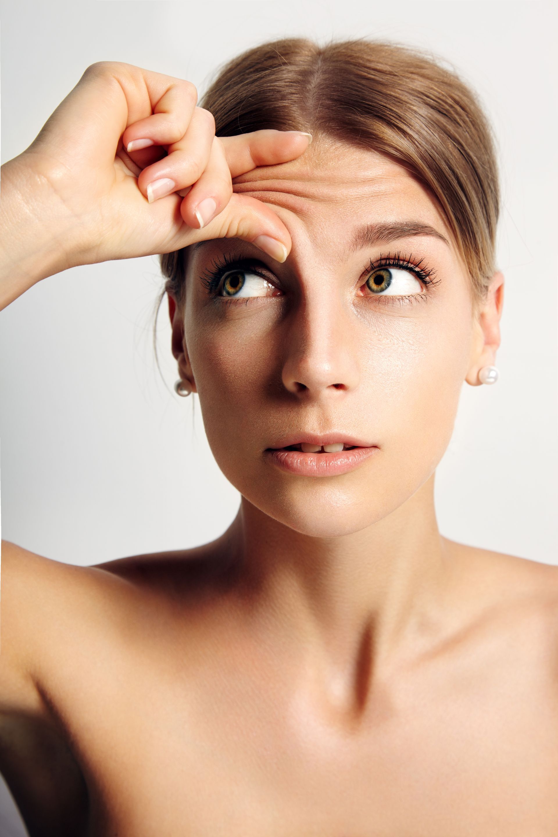 A woman is looking at her wrinkles on her forehead.