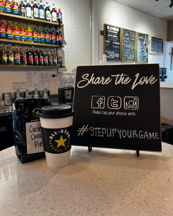 A coffee cup is sitting on a counter next to a sign that says share the love.