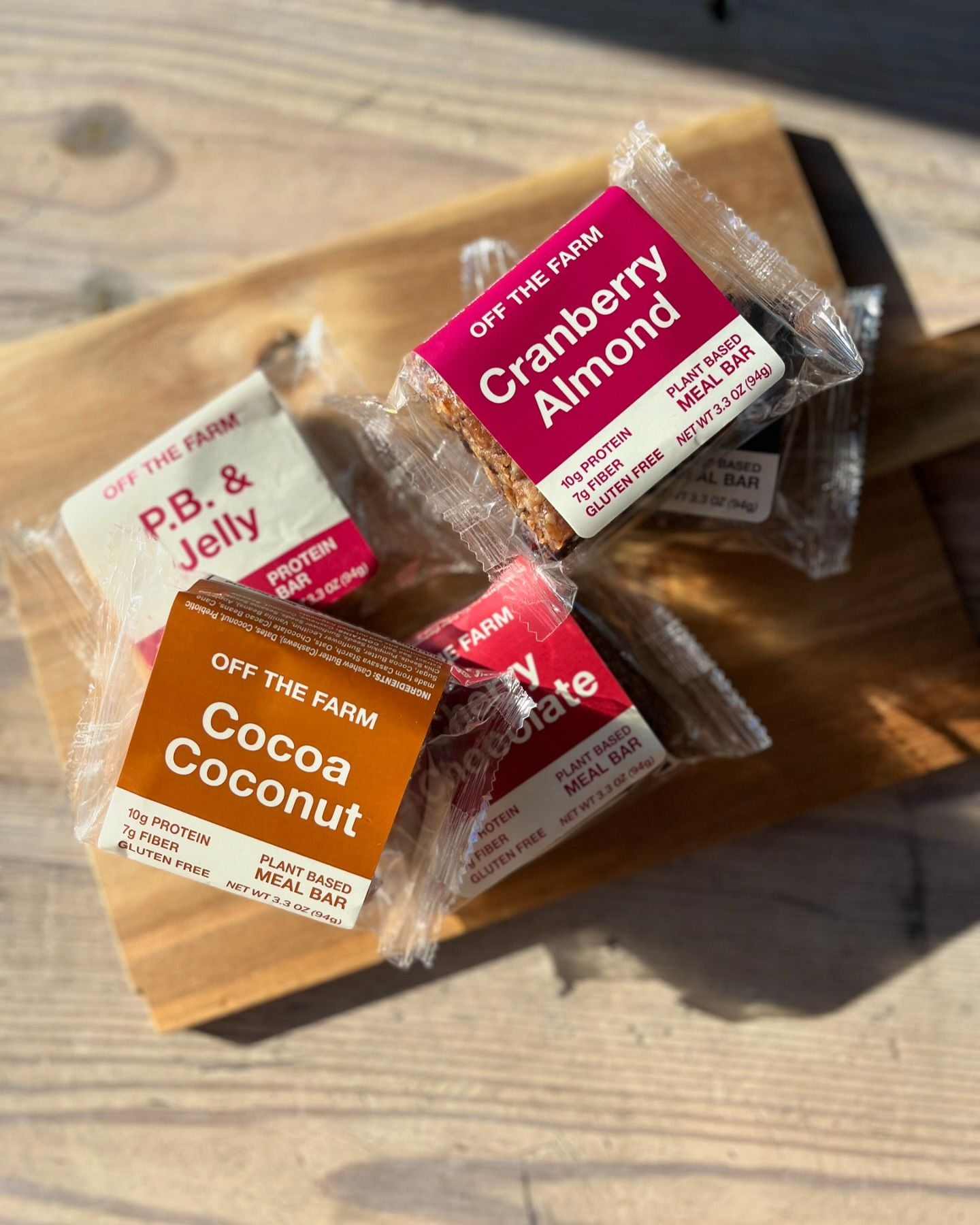 Three different flavors of granola bars are sitting on a wooden cutting board.