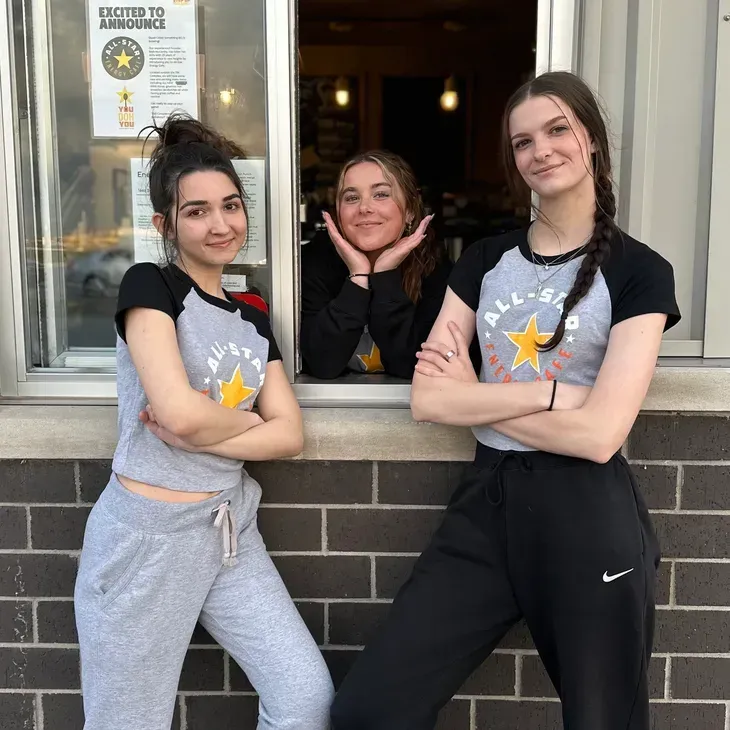 Three women are posing for a picture in front of a window that says closed to customer service