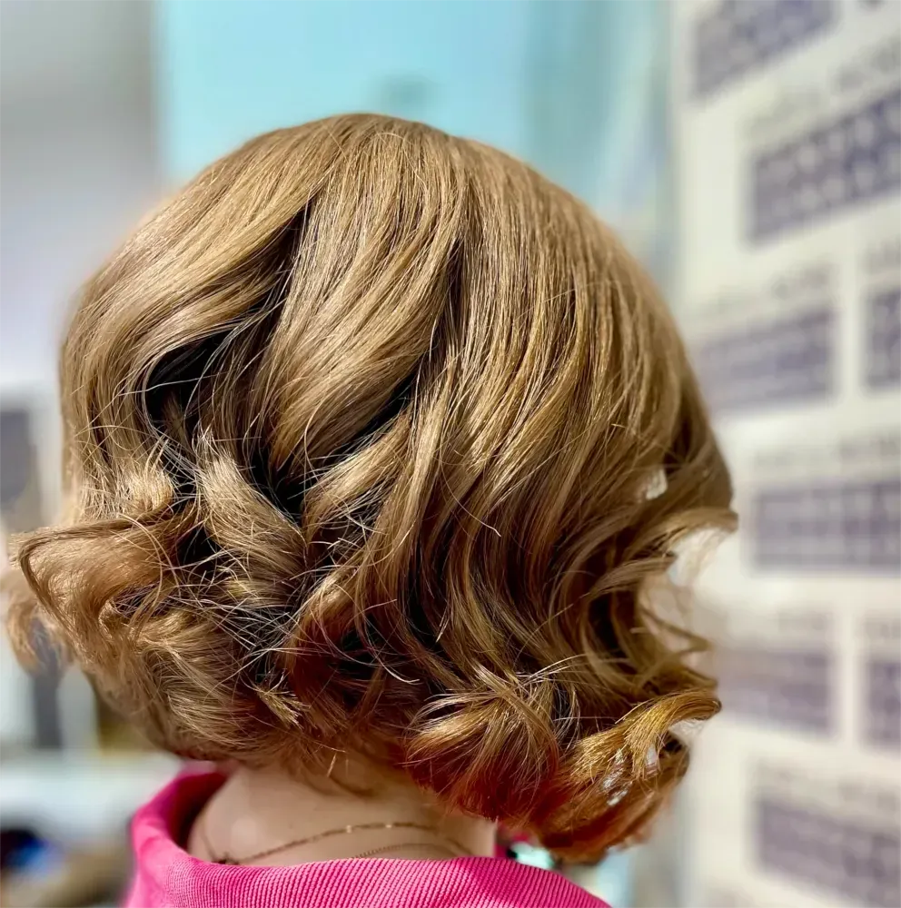 Frau mit kurzem, gewelltem, hellbraunem Haar, das zu einem Bob frisiert ist.