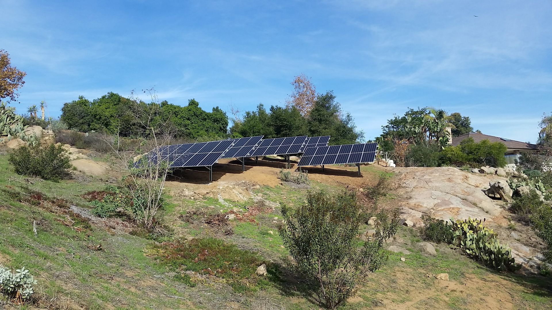 A row of solar panels are sitting on top of a hill.