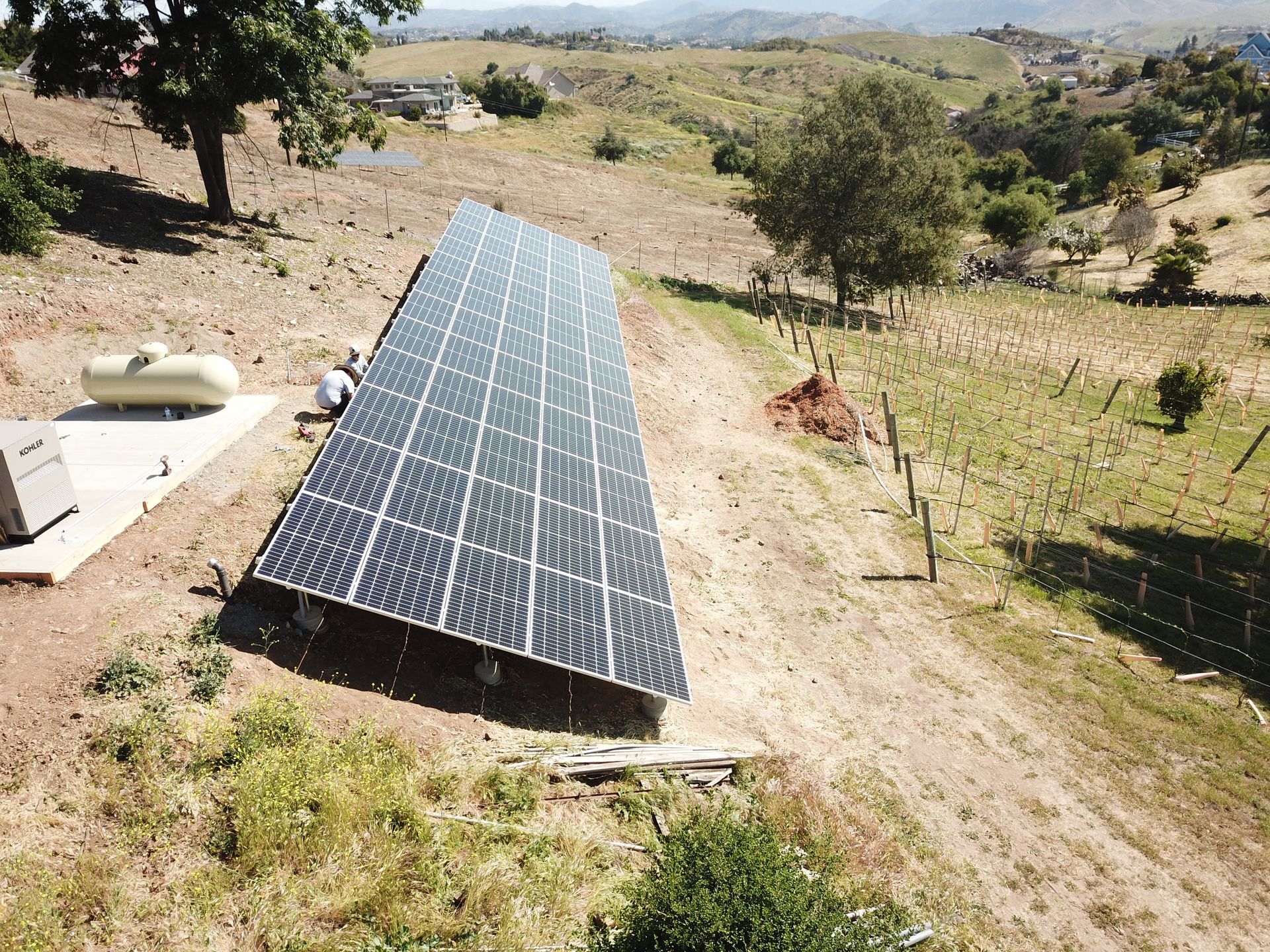A row of solar panels are sitting on top of a dirt hill.