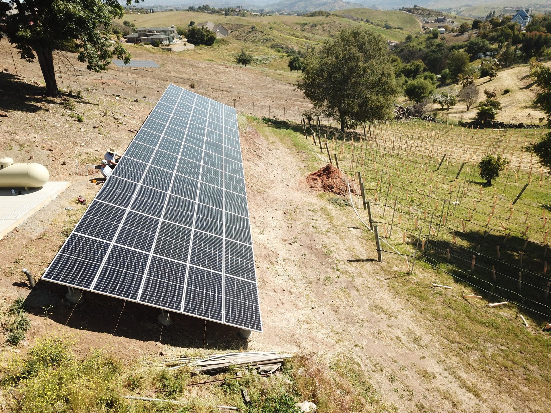 A row of solar panels are sitting on top of a dirt field.