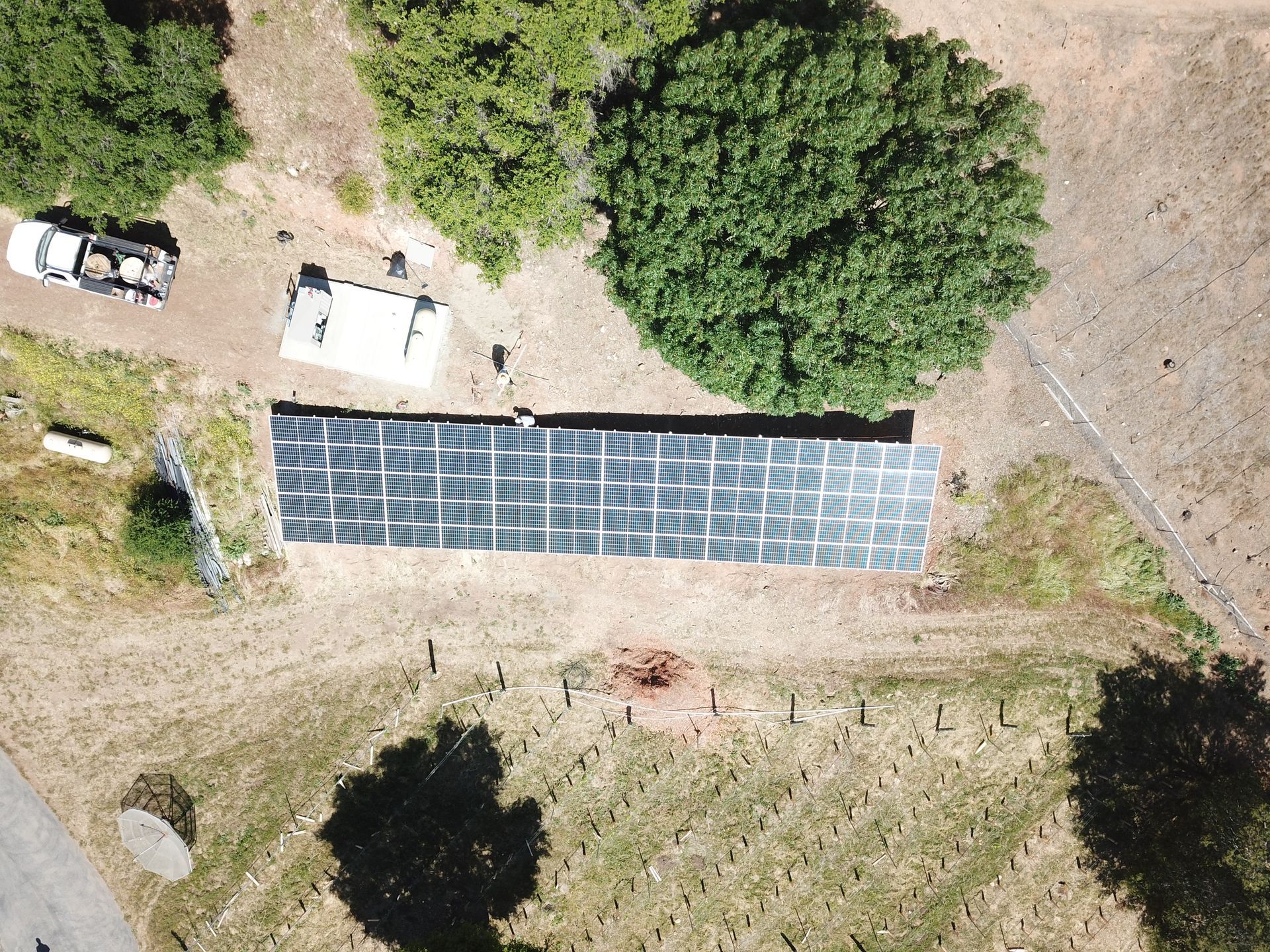 An aerial view of a solar panel installation in a field surrounded by trees.