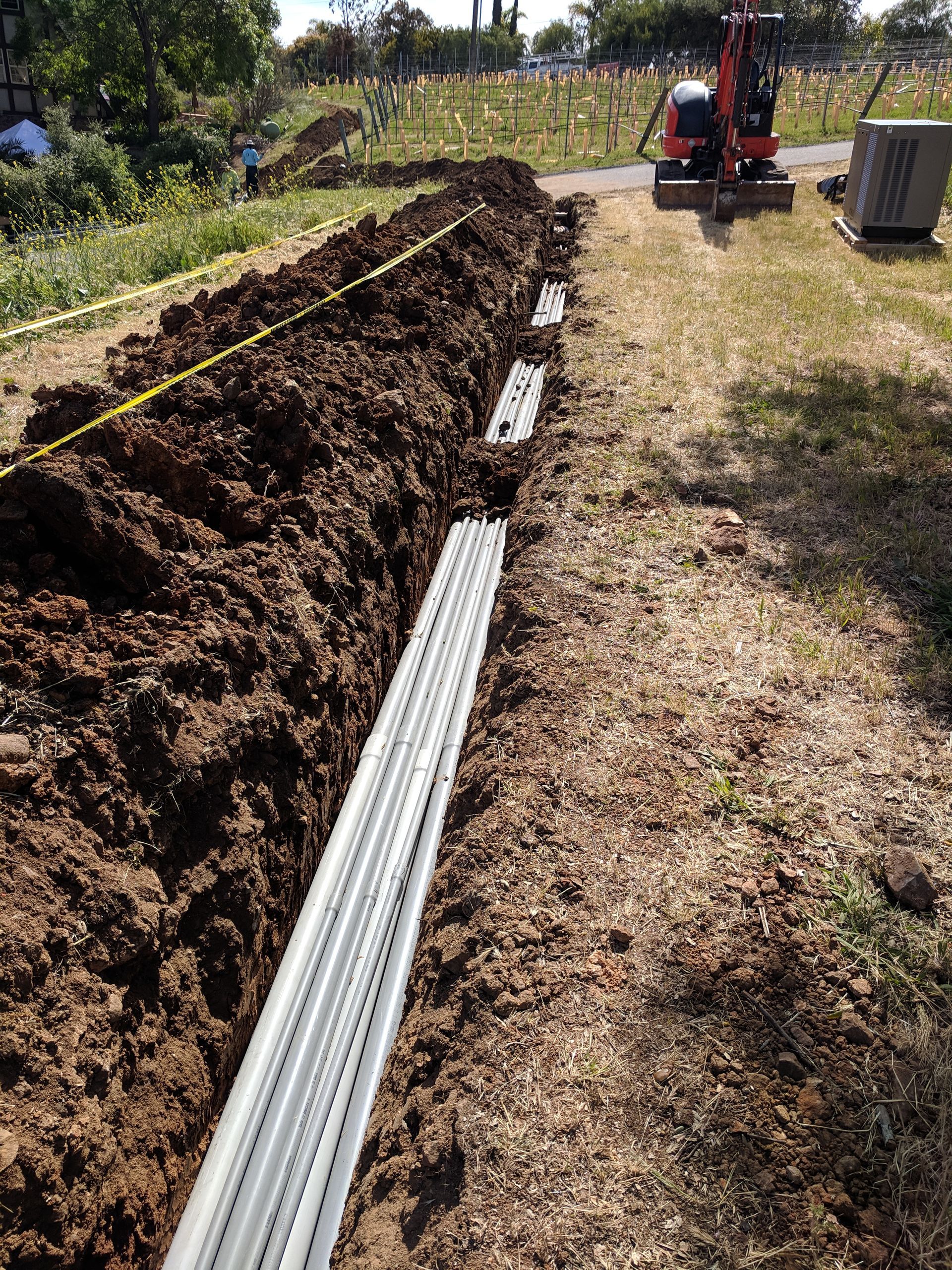 A hose is being installed in the dirt next to a road.