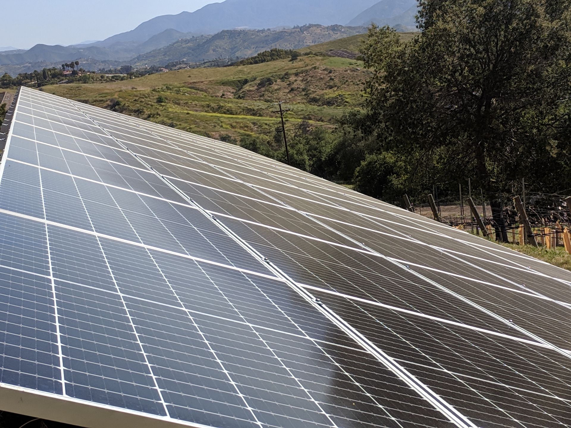 A row of solar panels on a roof with mountains in the background