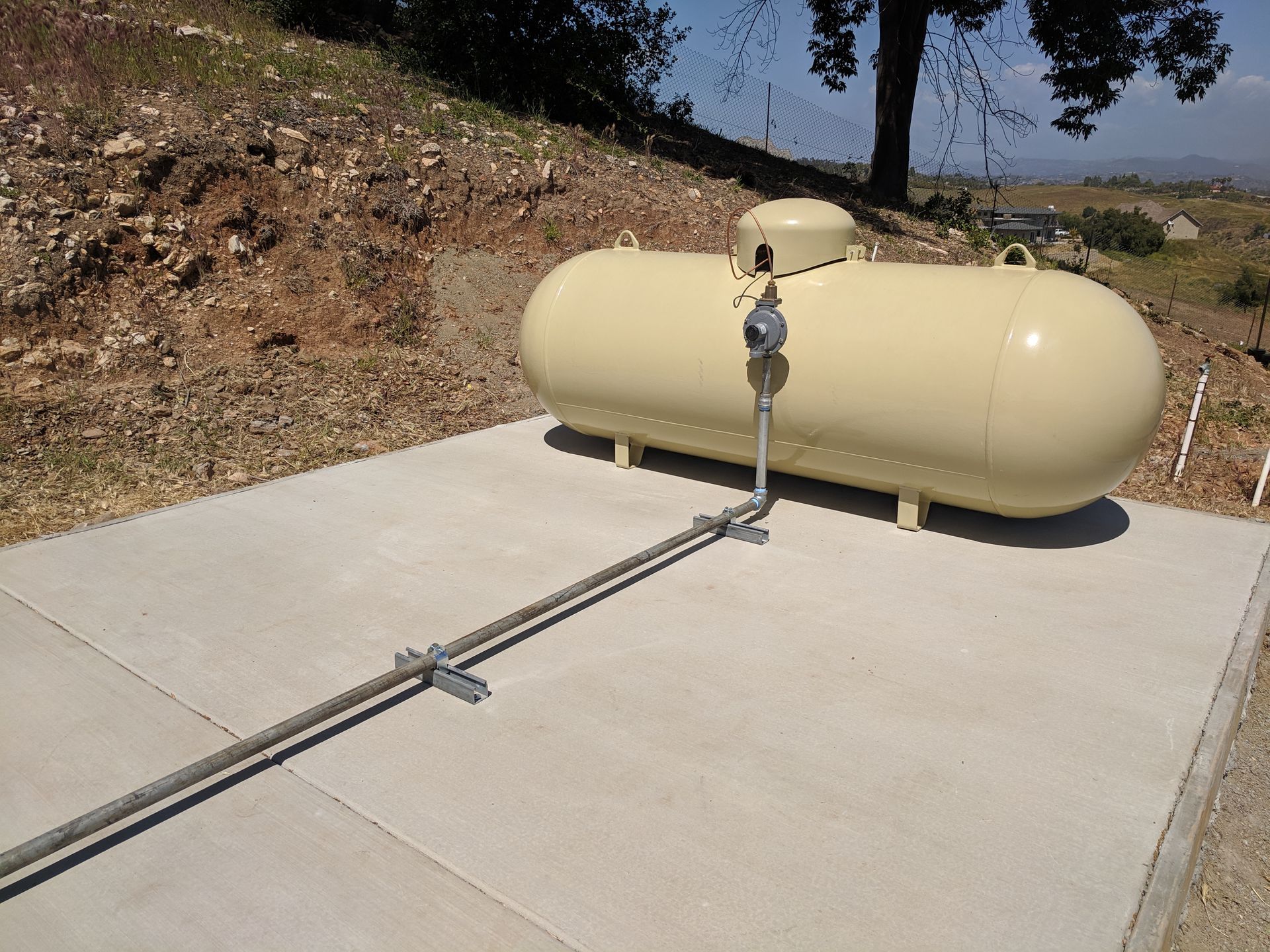 A large yellow propane tank is sitting on a concrete surface.