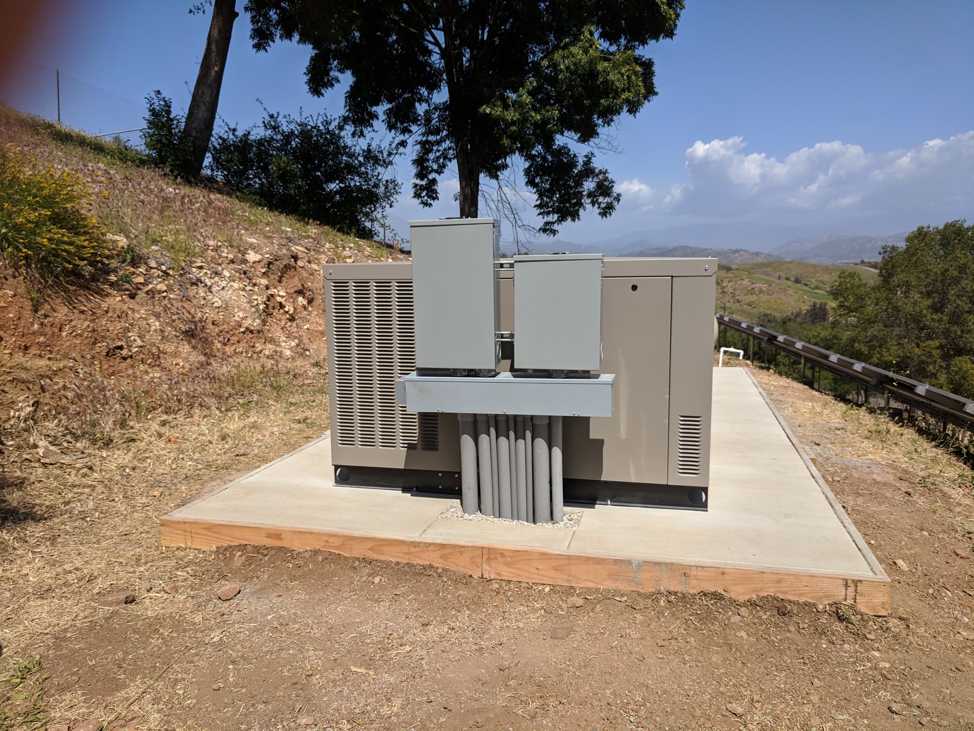 A large electrical box is sitting on top of a dirt hill