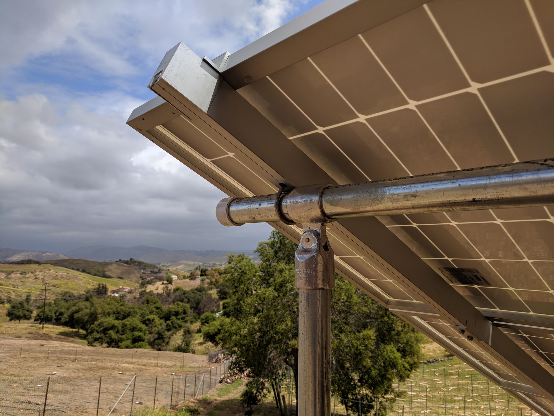 A close up of a solar panel with a fence in the background