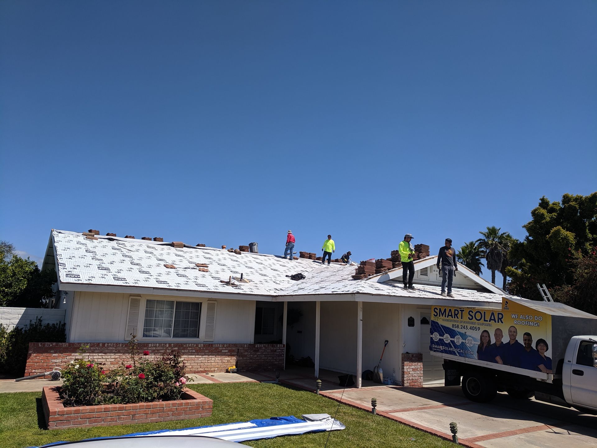A group of people are working on the roof of a house.