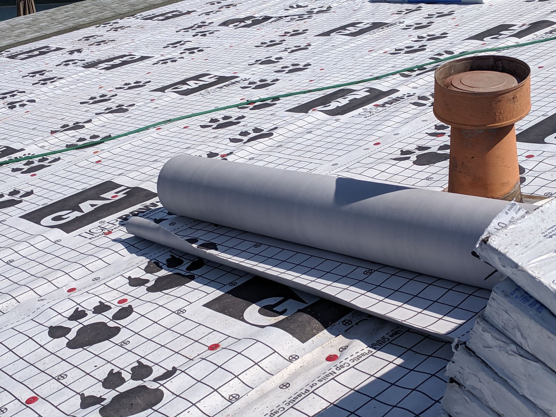 A roof with a chimney and a roll of insulation on it.