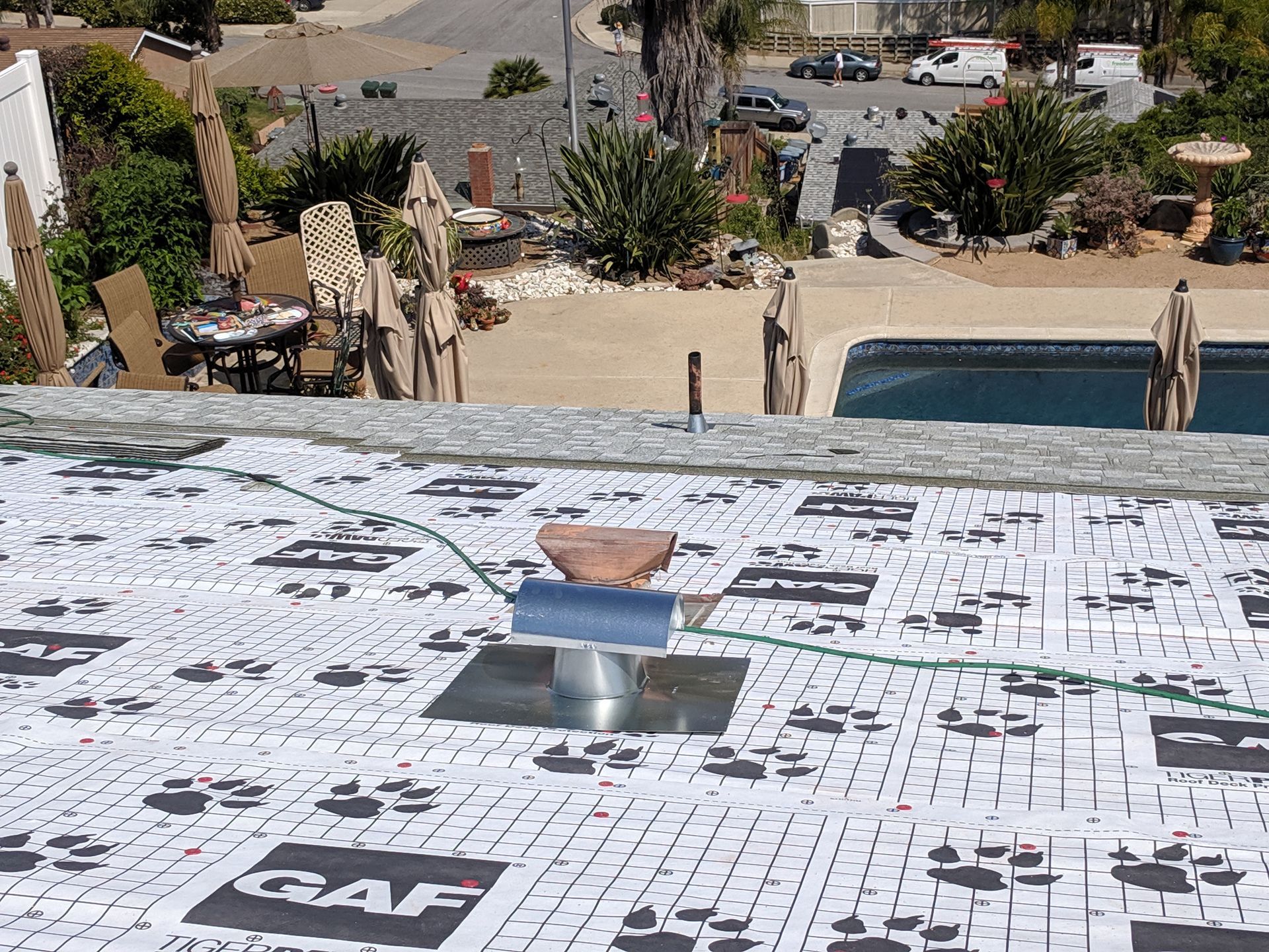 A roof with a drain hole in it and a pool in the background