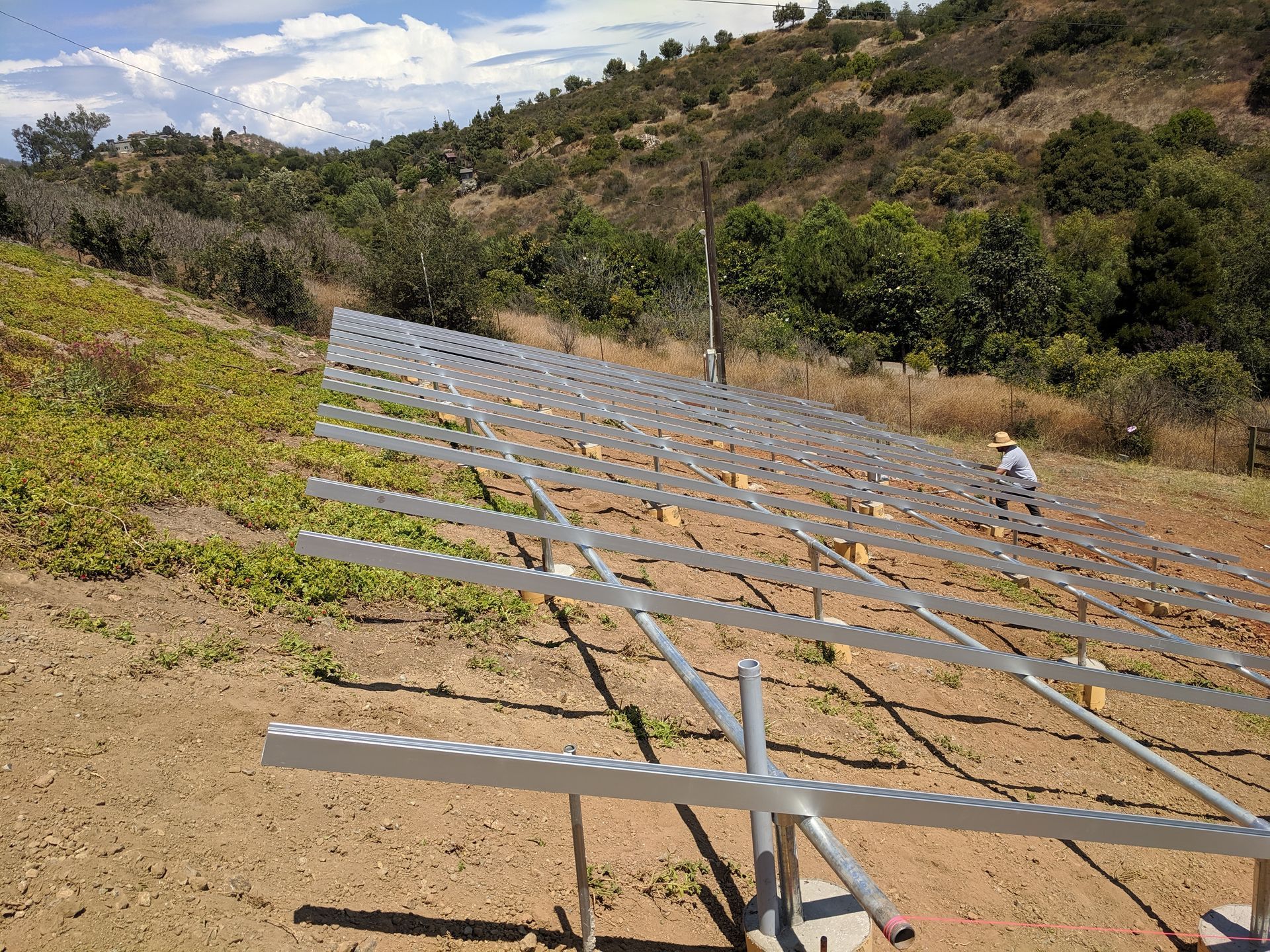 A row of solar panels sitting on top of a dirt field.