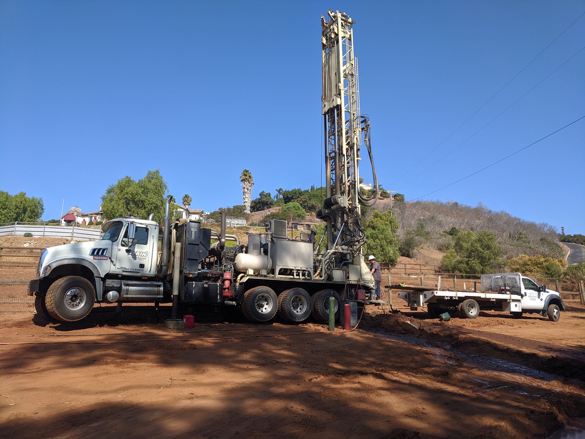 A truck is parked in a dirt field next to a crane.