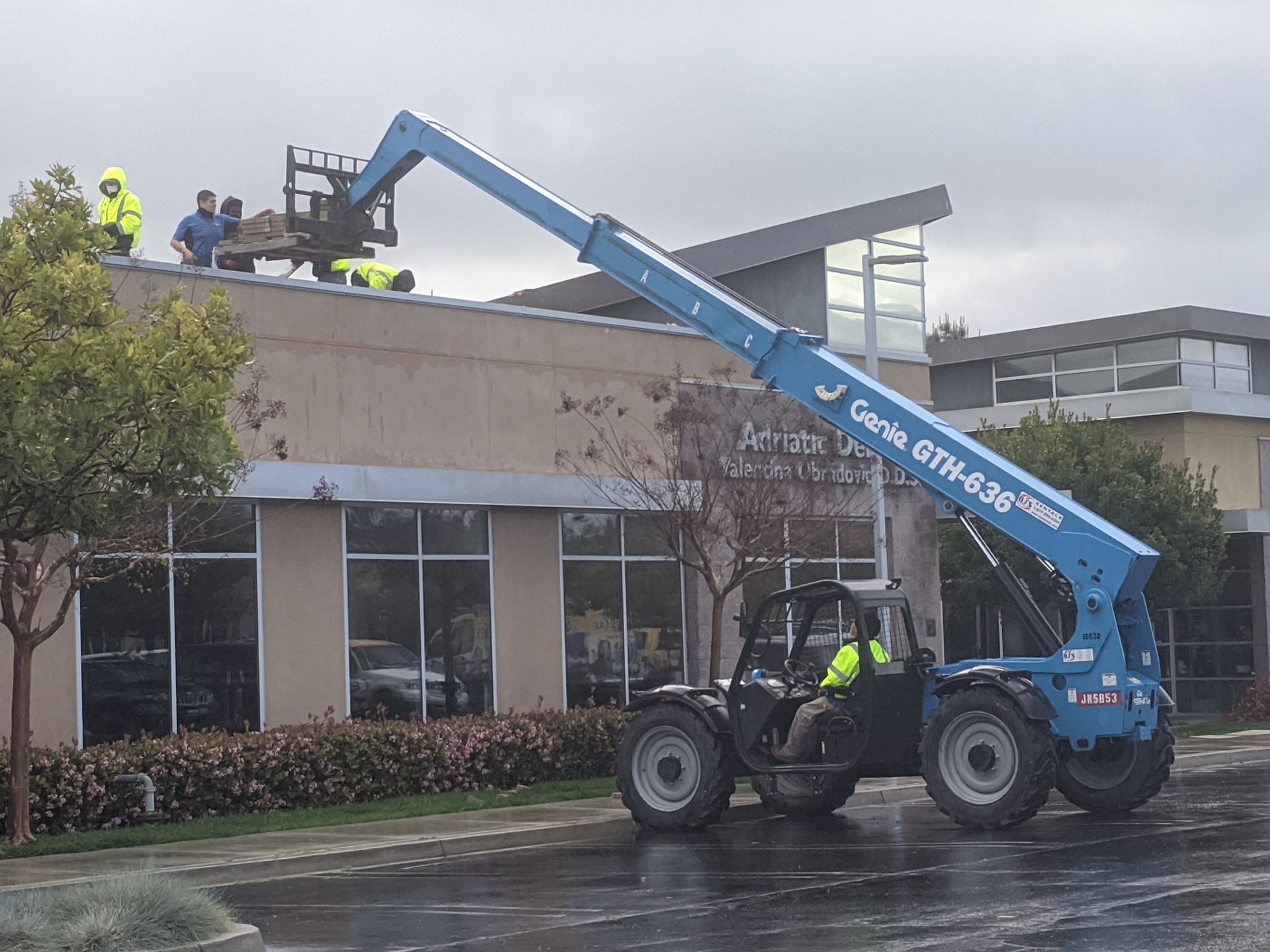 A blue genie tractor is parked in front of a building