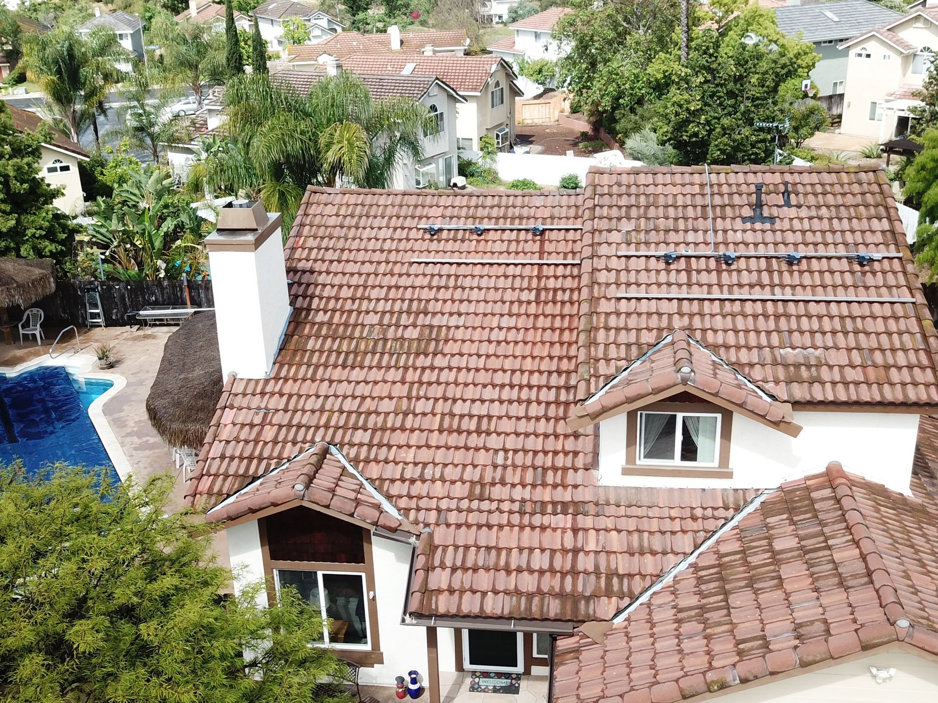 An aerial view of a house with a tiled roof and a pool.