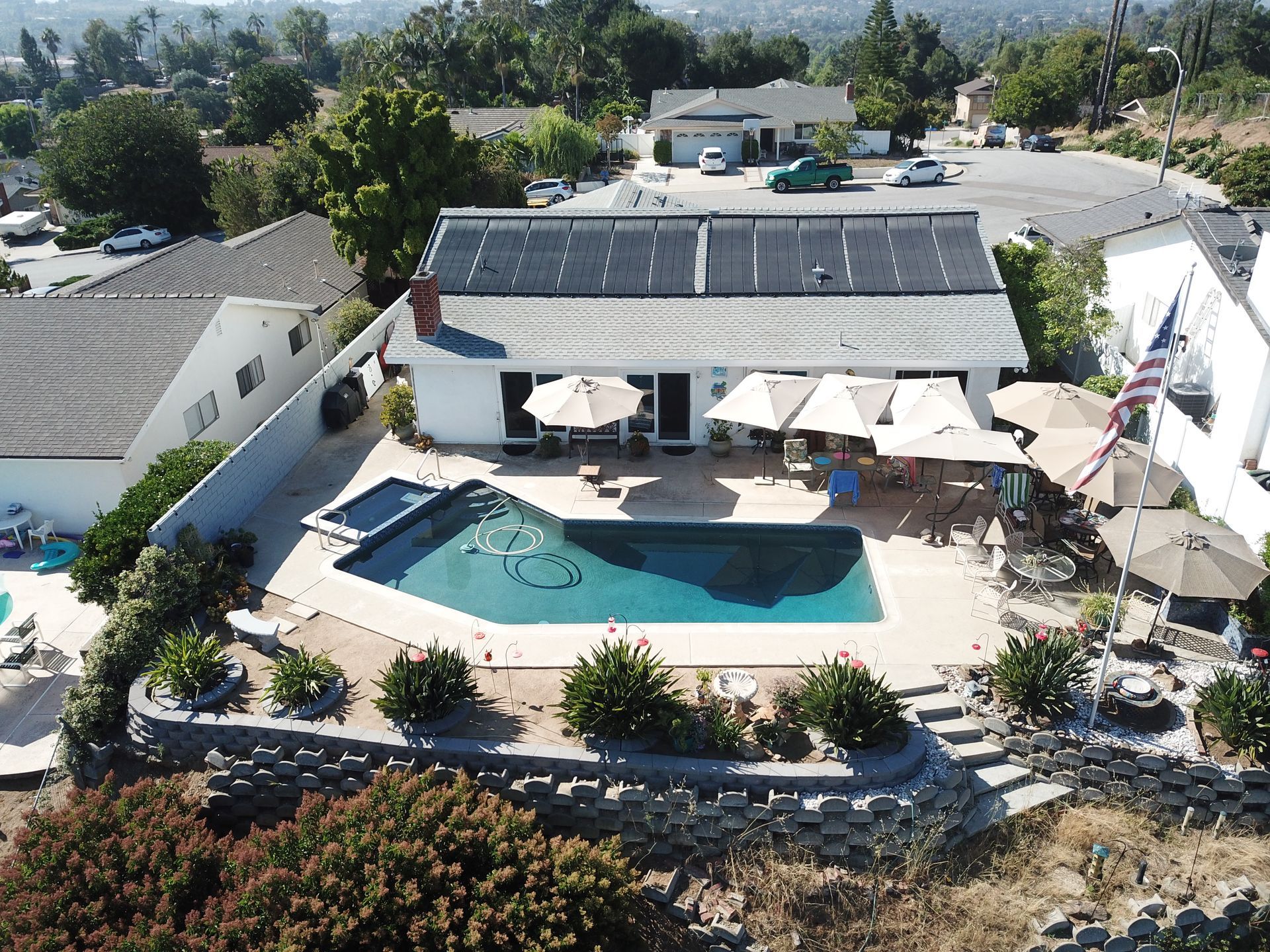 An aerial view of a house with a pool and umbrellas