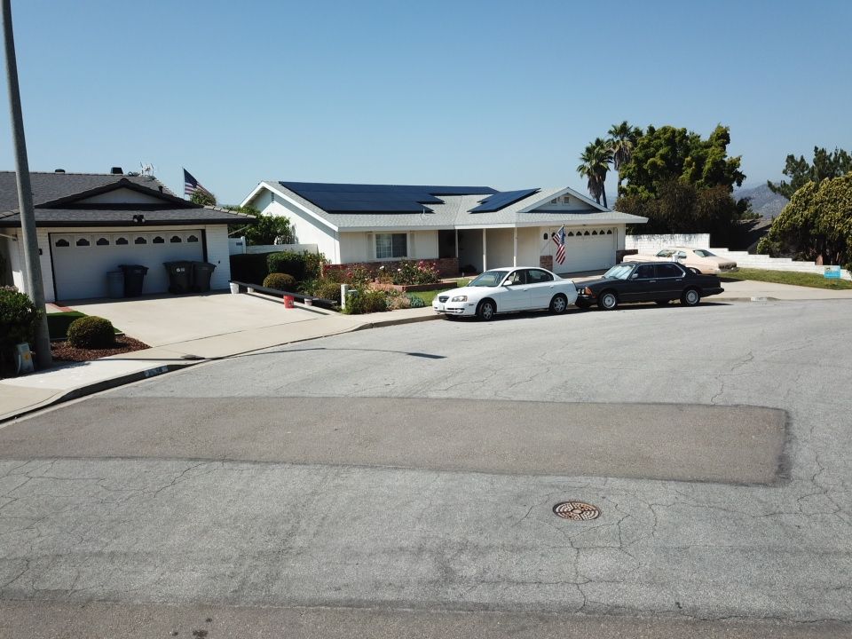 Cars are parked in front of a house with solar panels on the roof