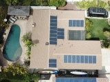 An aerial view of a house with solar panels on the roof and a pool.