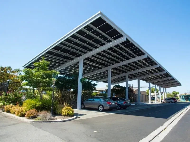 A car is parked under a canopy with solar panels.