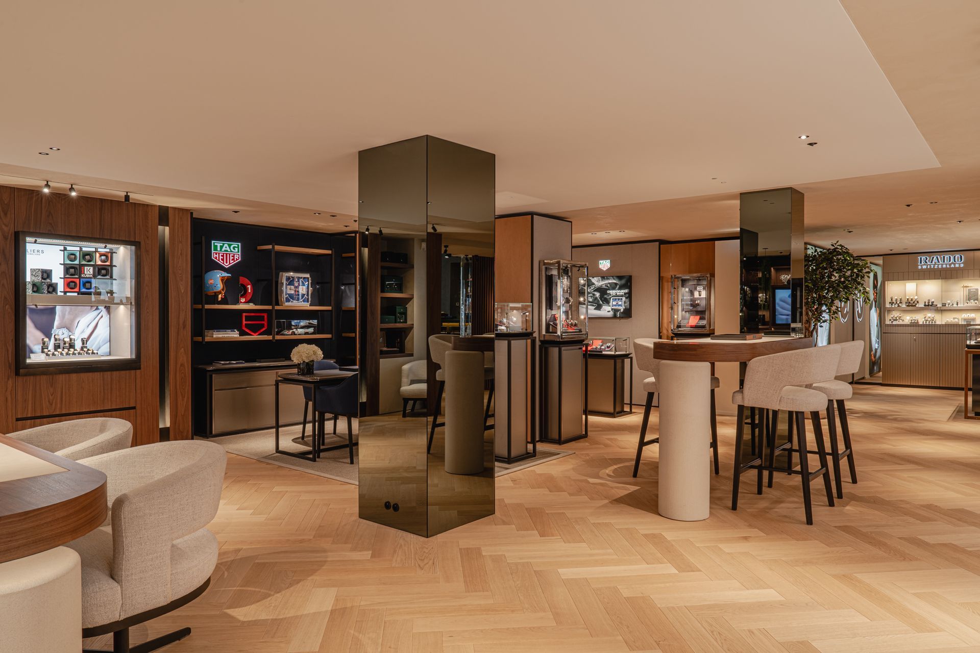 Interieur van een luxe horlogewinkel met vitrines, zitgedeeltes en een reflecterende pilaar.