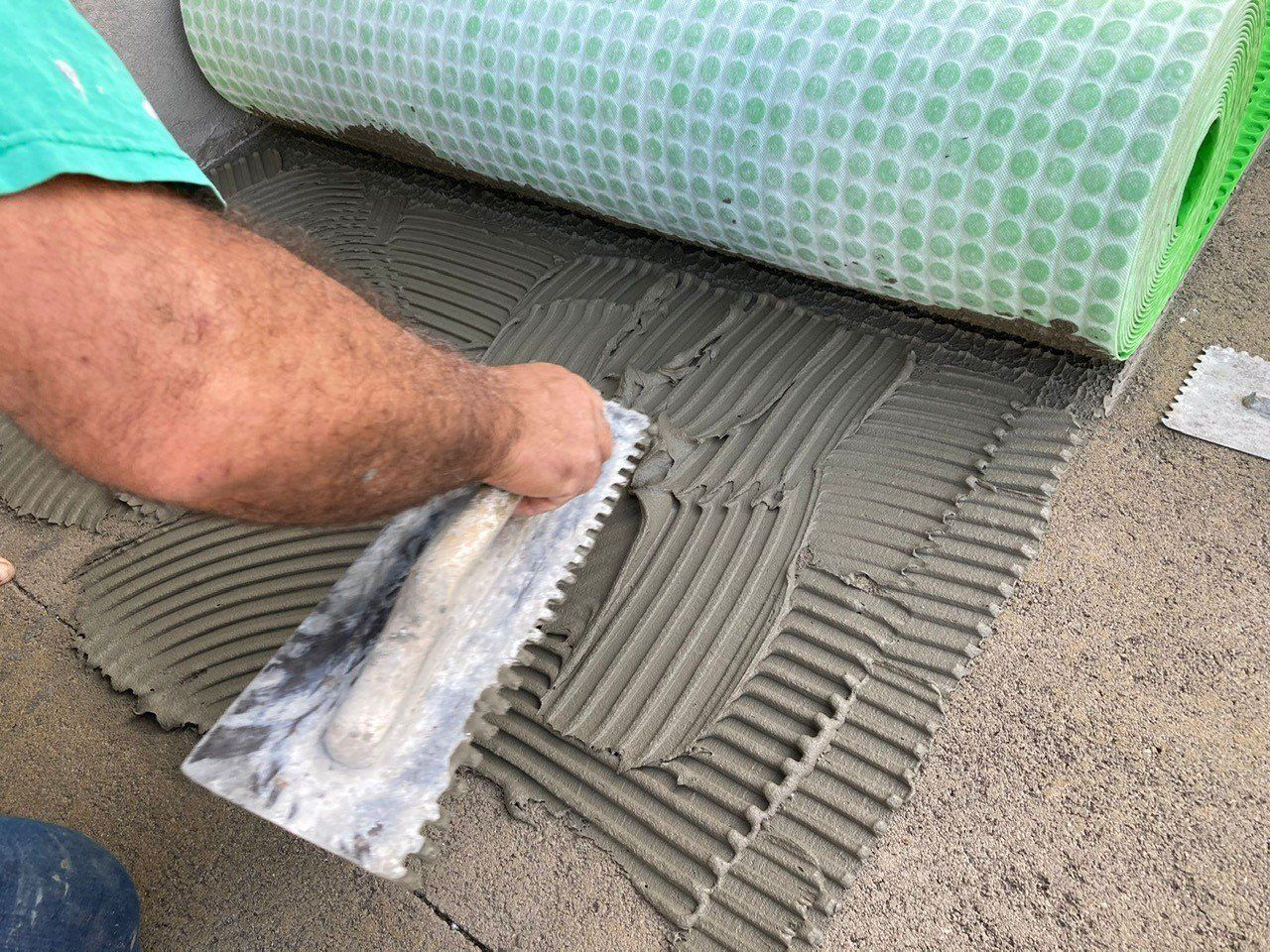 Un uomo sta posando le piastrelle sul pavimento con una cazzuola.