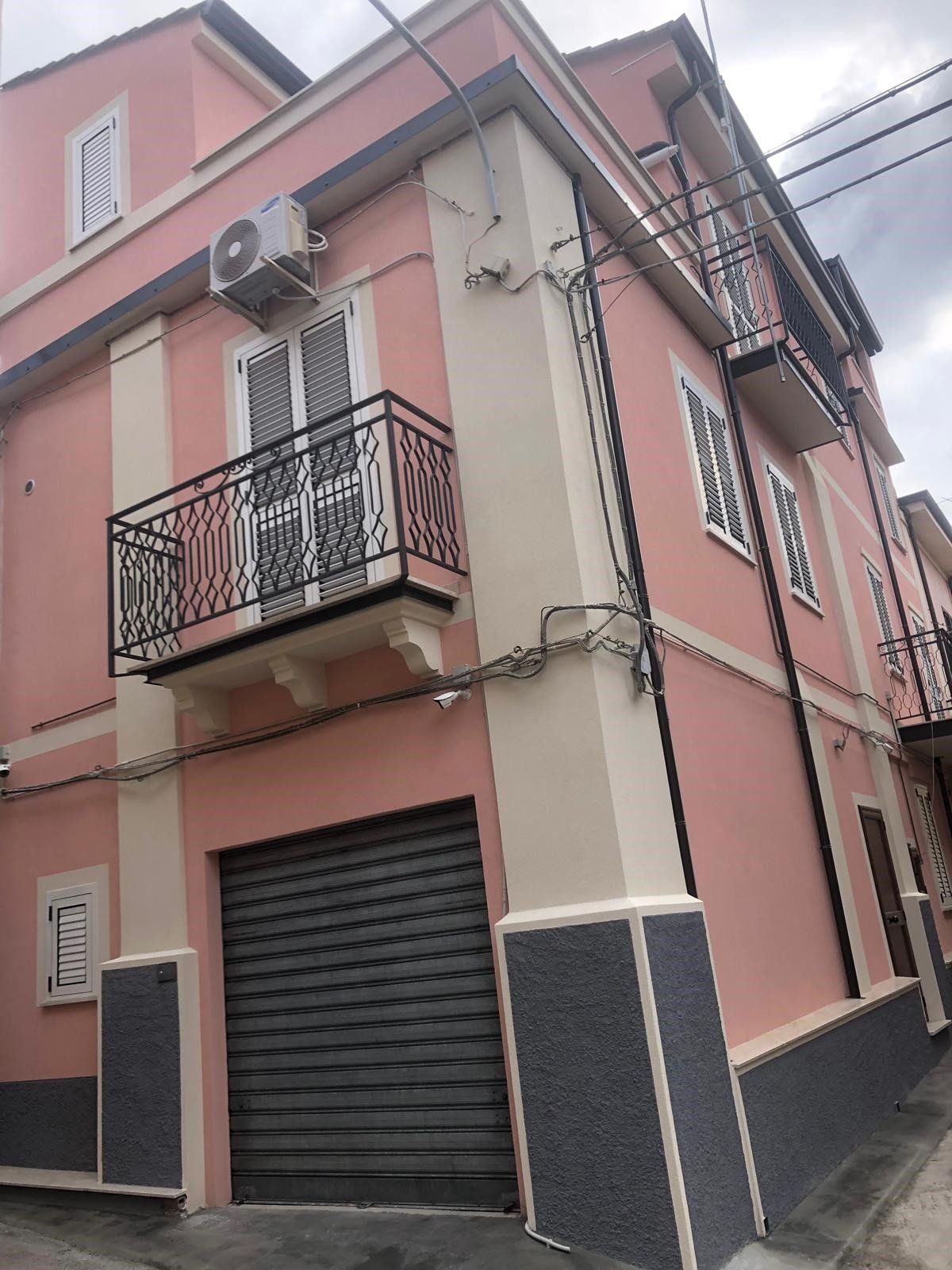 Un edificio rosa e bianco con un balcone e un garage