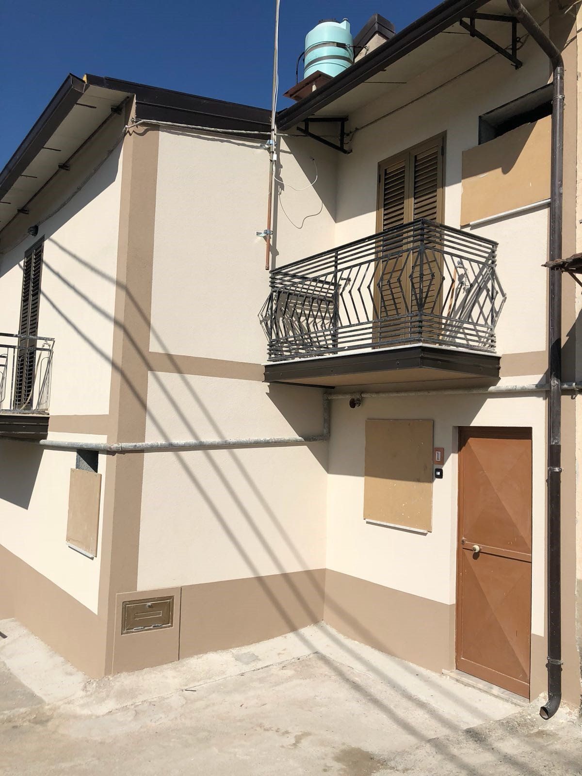 Un edificio bianco con un balcone e una porta marrone