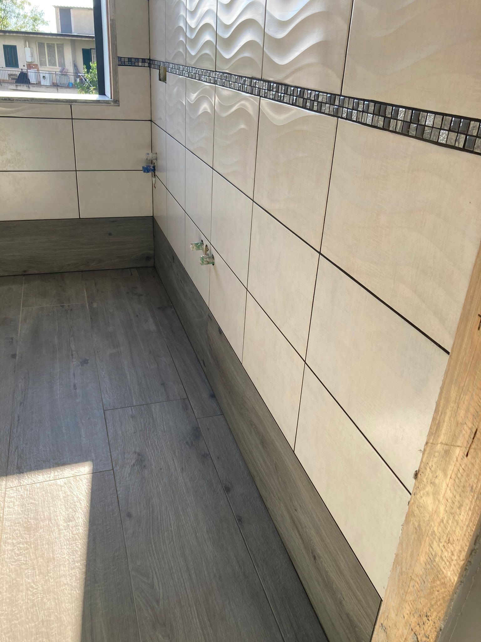 Una stanza con pavimento in legno e piastrelle bianche alle pareti.