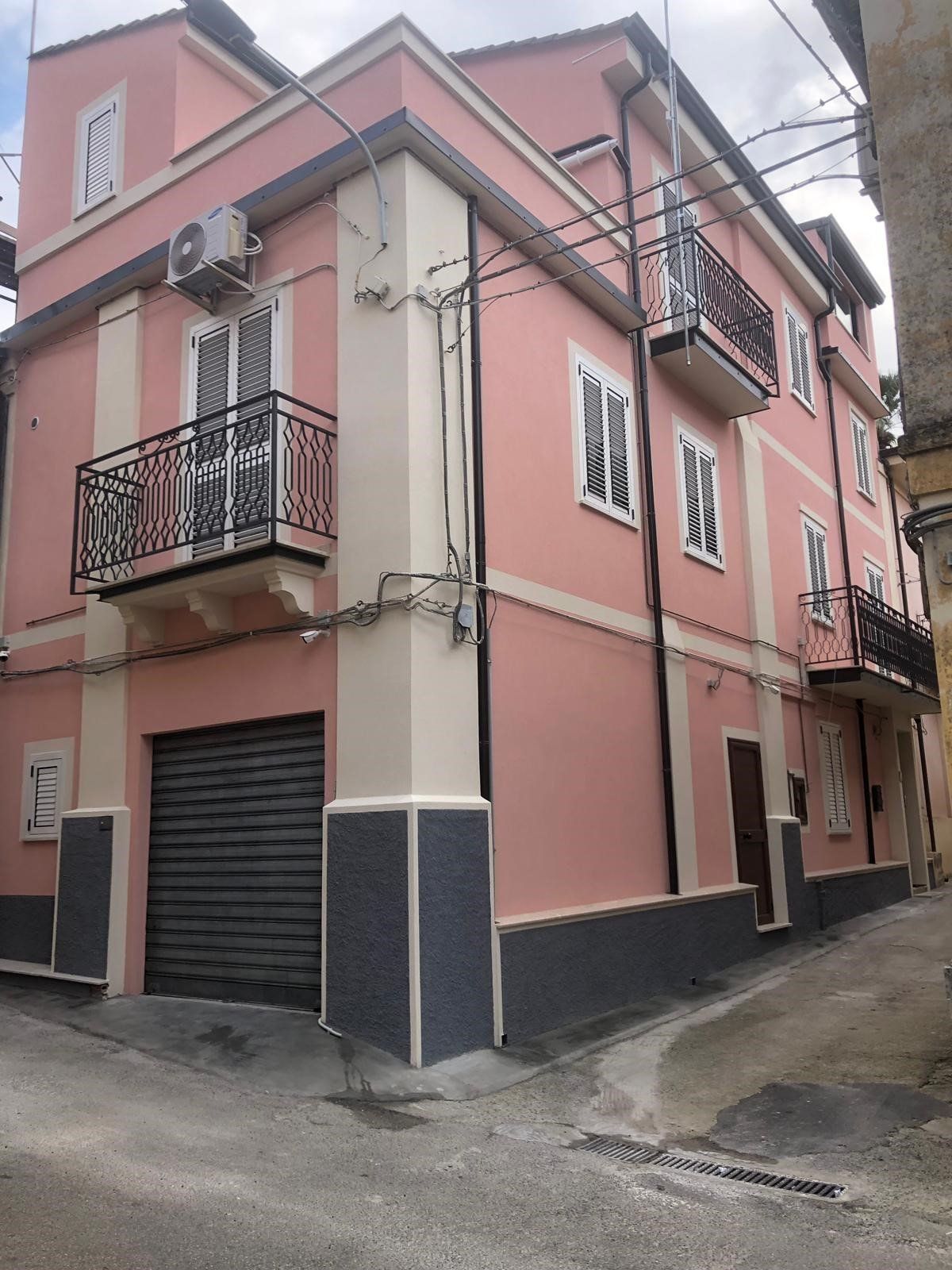 Un edificio rosa e bianco con un balcone e un garage