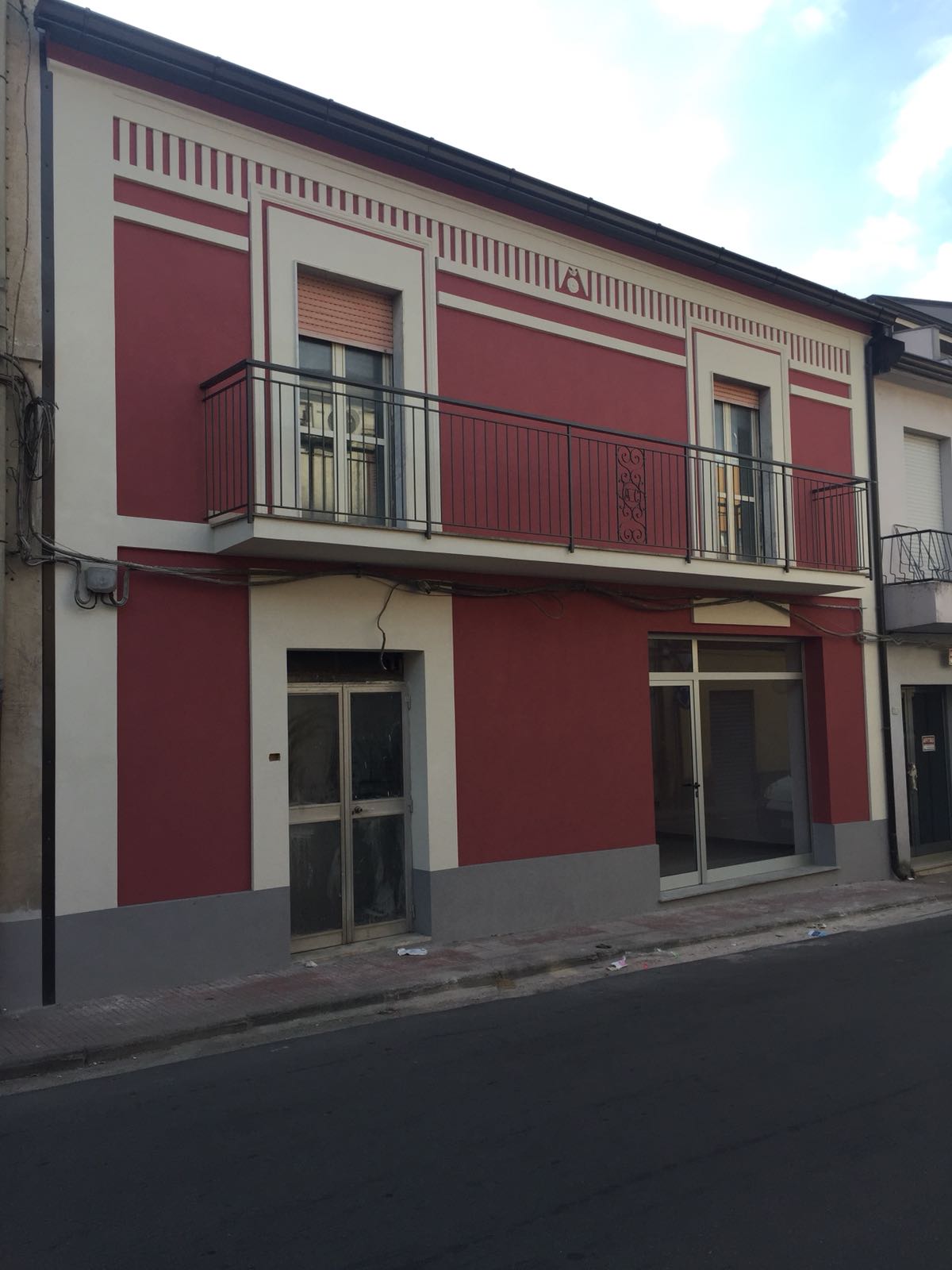 Un edificio rosso e bianco con un balcone al secondo piano