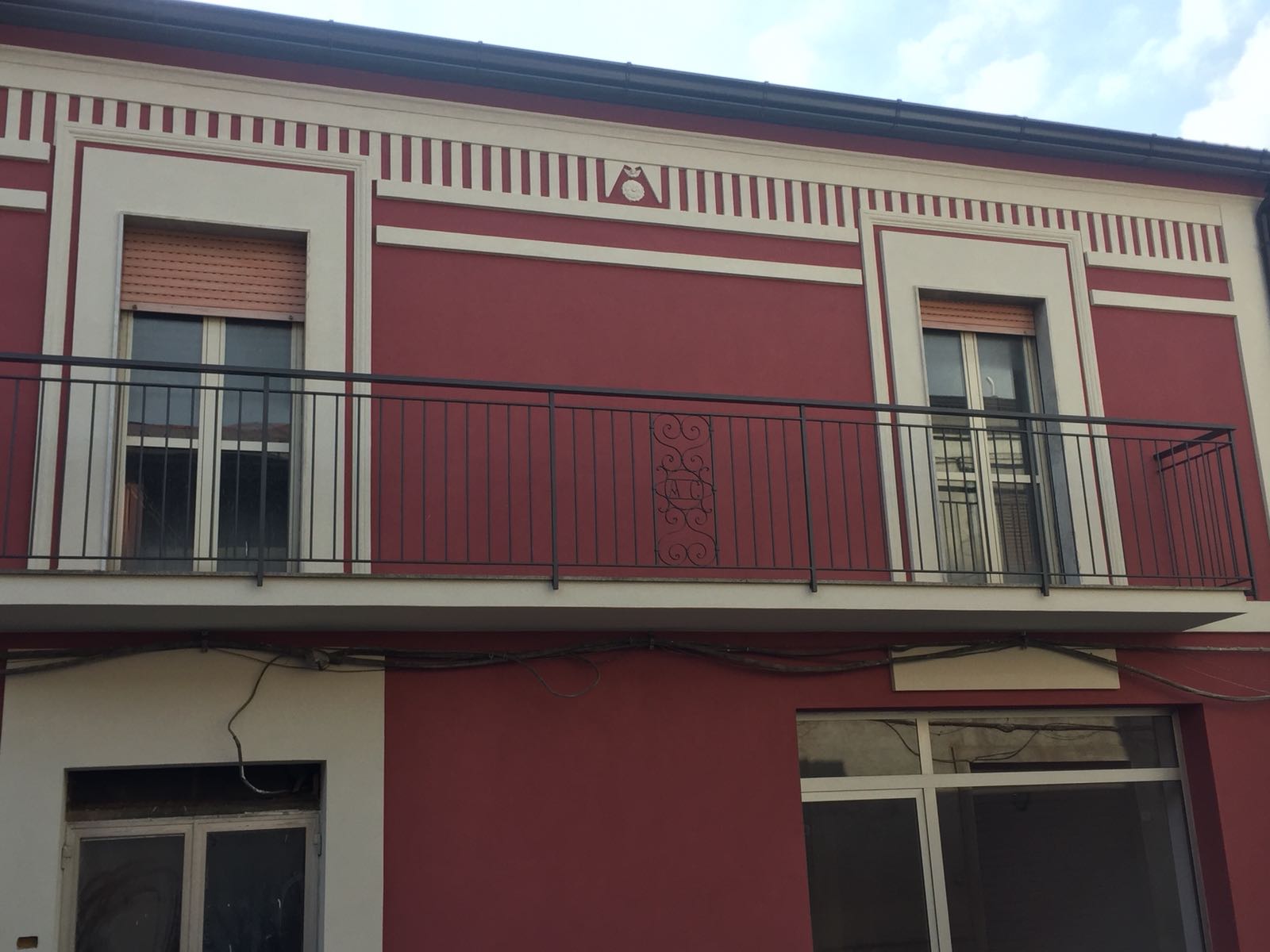 Un edificio rosso con un balcone al secondo piano