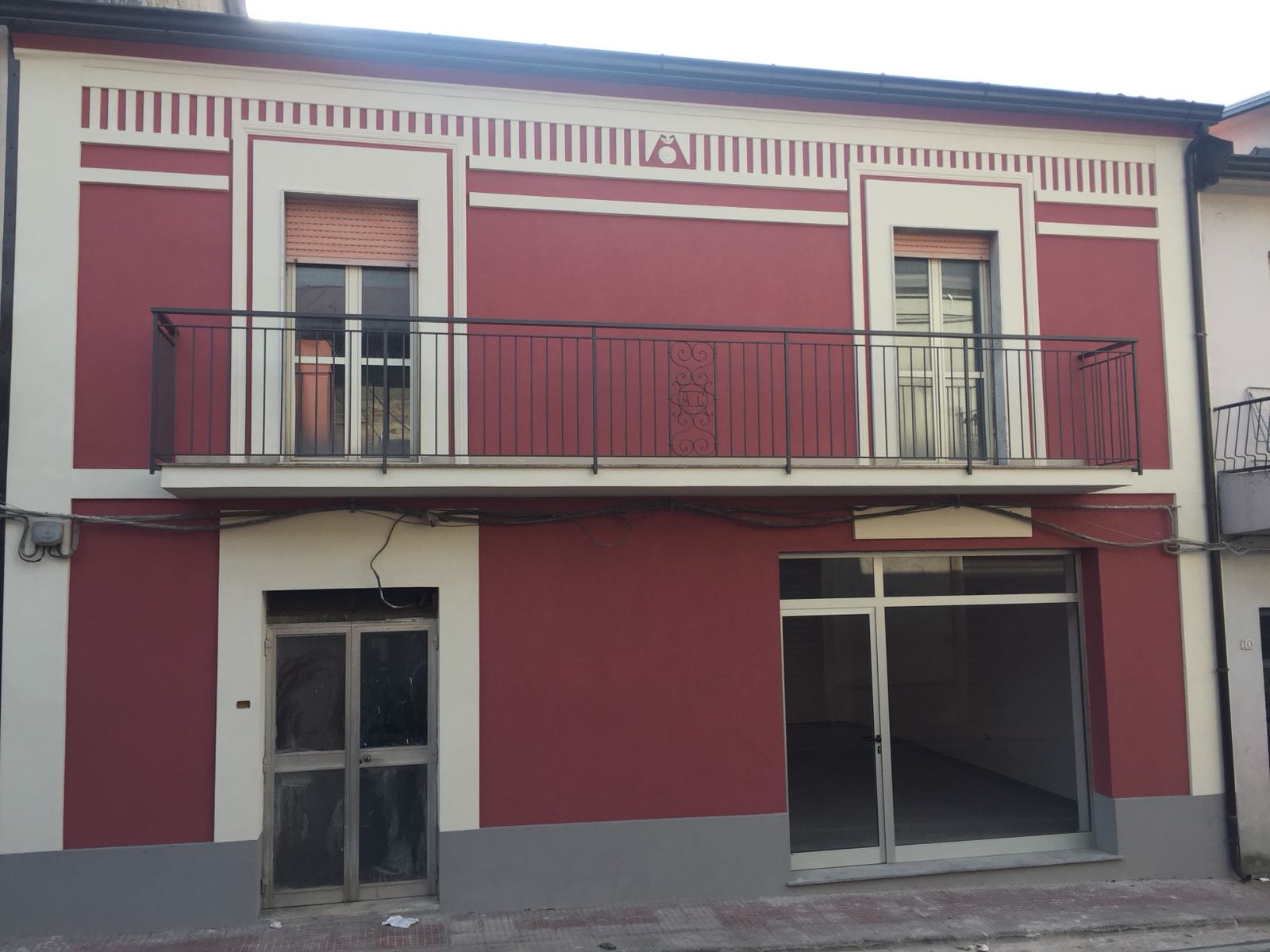 Un edificio rosso e bianco con un balcone al secondo piano