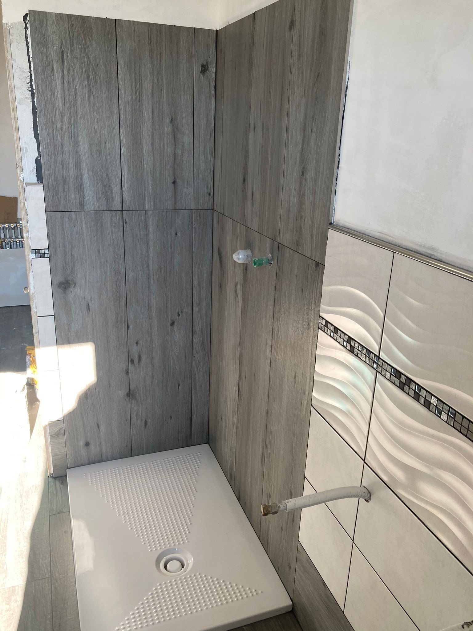Un bagno con box doccia e pareti piastrellate.
